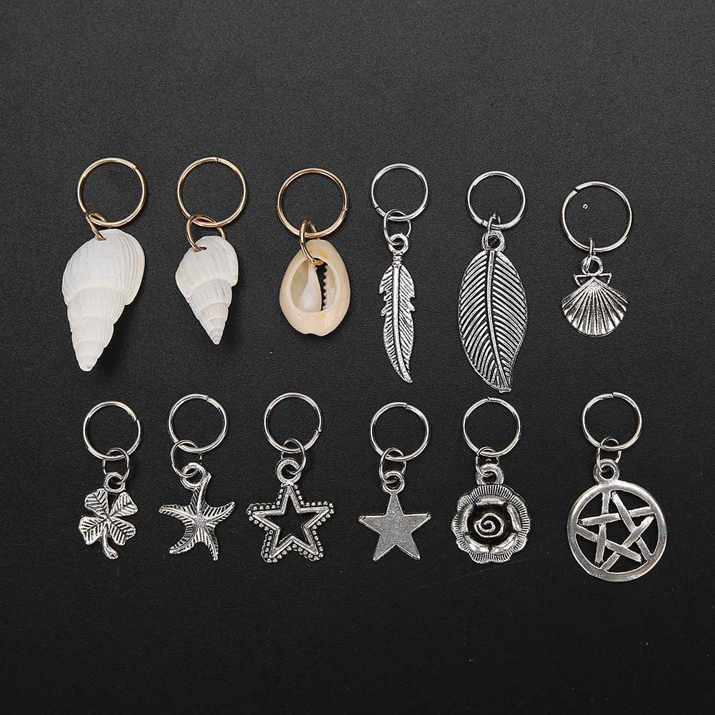 Haaraccessoires, darunter Anhänger mit Muscheln, Blättern, Sternen und Kreisen. Schwarzer Hintergrund.