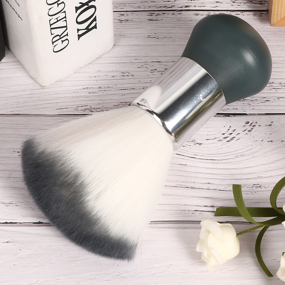Make-up-Pinsel mit weißen und grauen Borsten und einem dunkelgrünen Griff, auf Holz liegend.