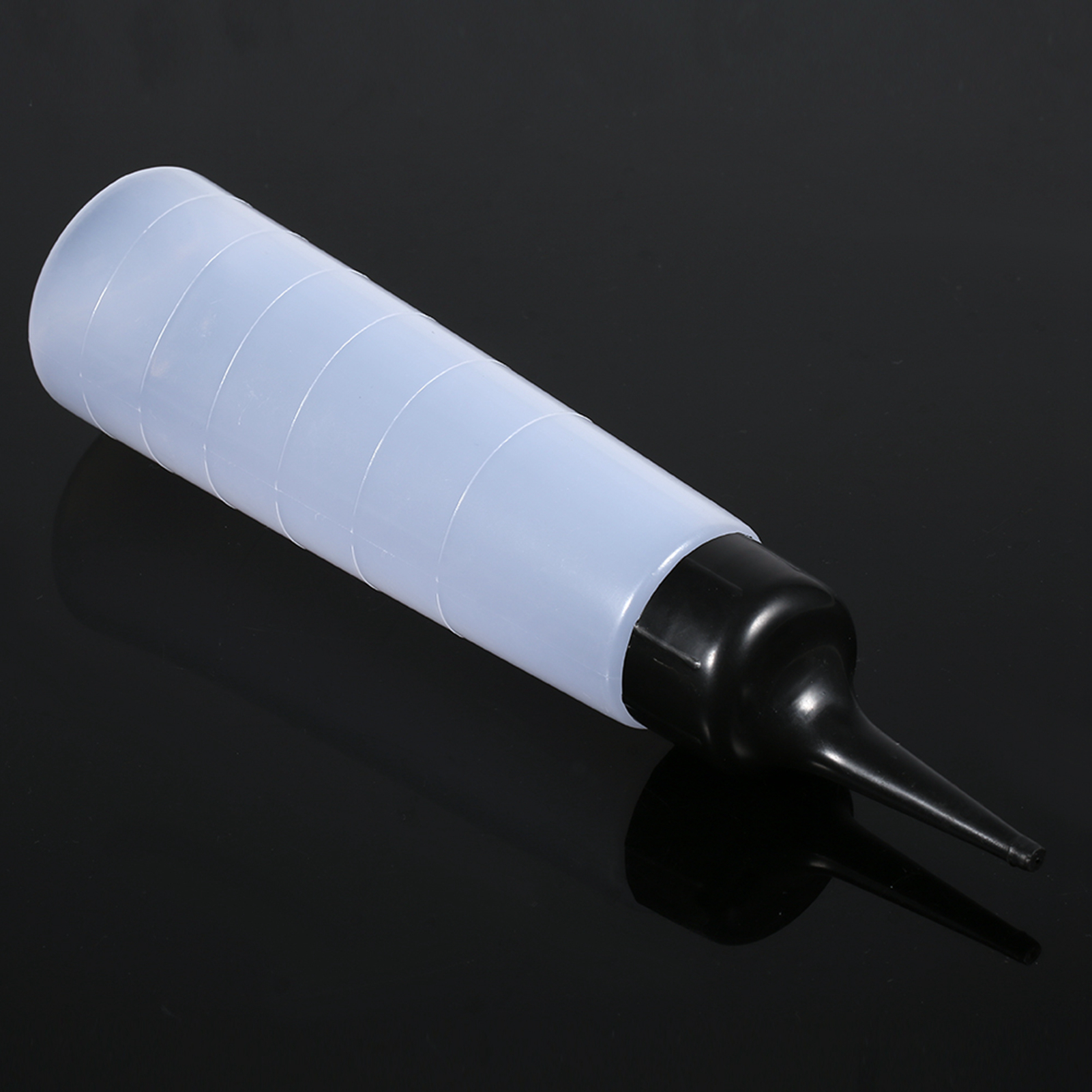 Eine weiße Plastikflasche mit schwarzer Düse, die auf einer schwarzen Oberfläche liegt.