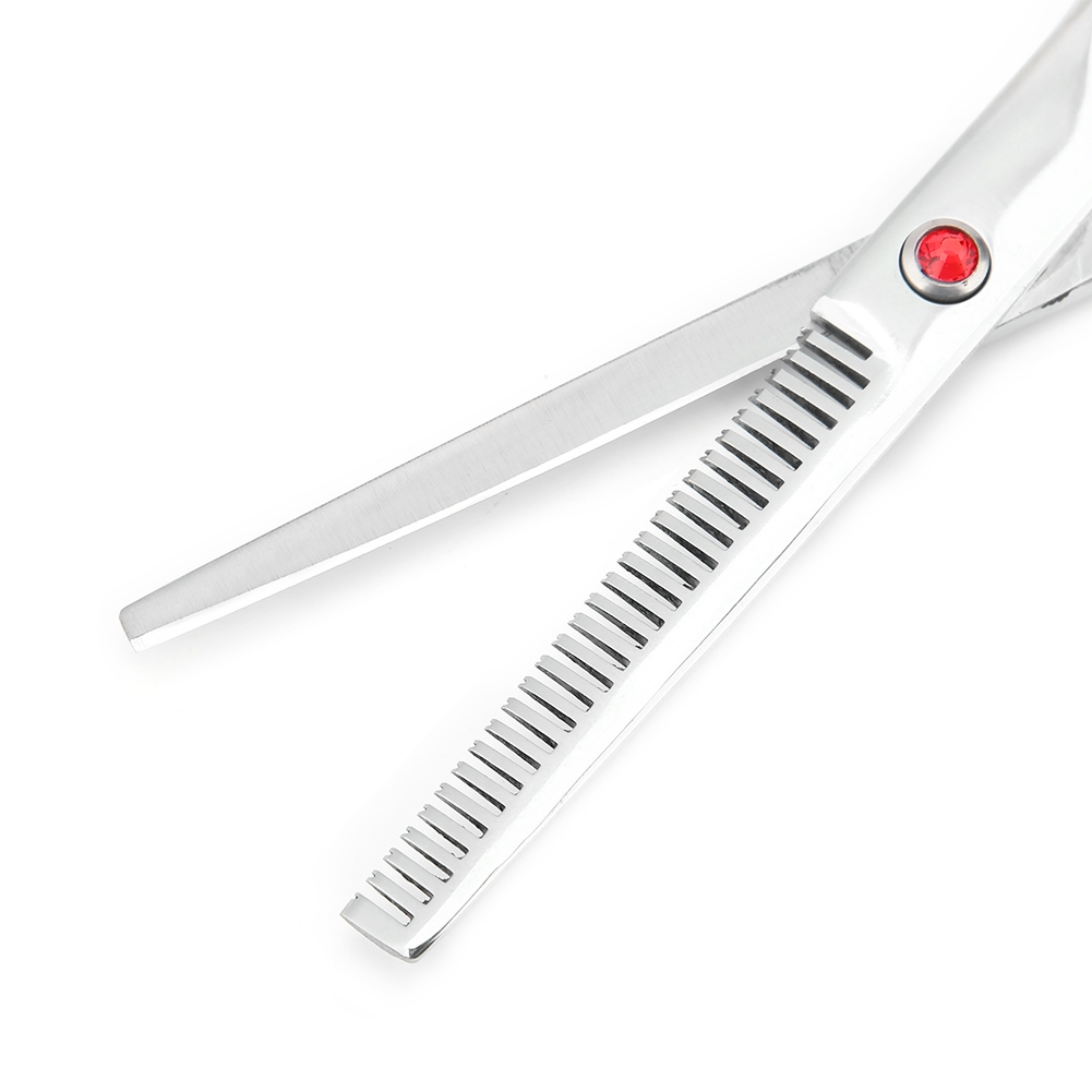 Friseurschere mit roter Schraube. Eine Klinge hat Zähne. Die Schere ist geöffnet und liegt auf weißem Untergrund.
