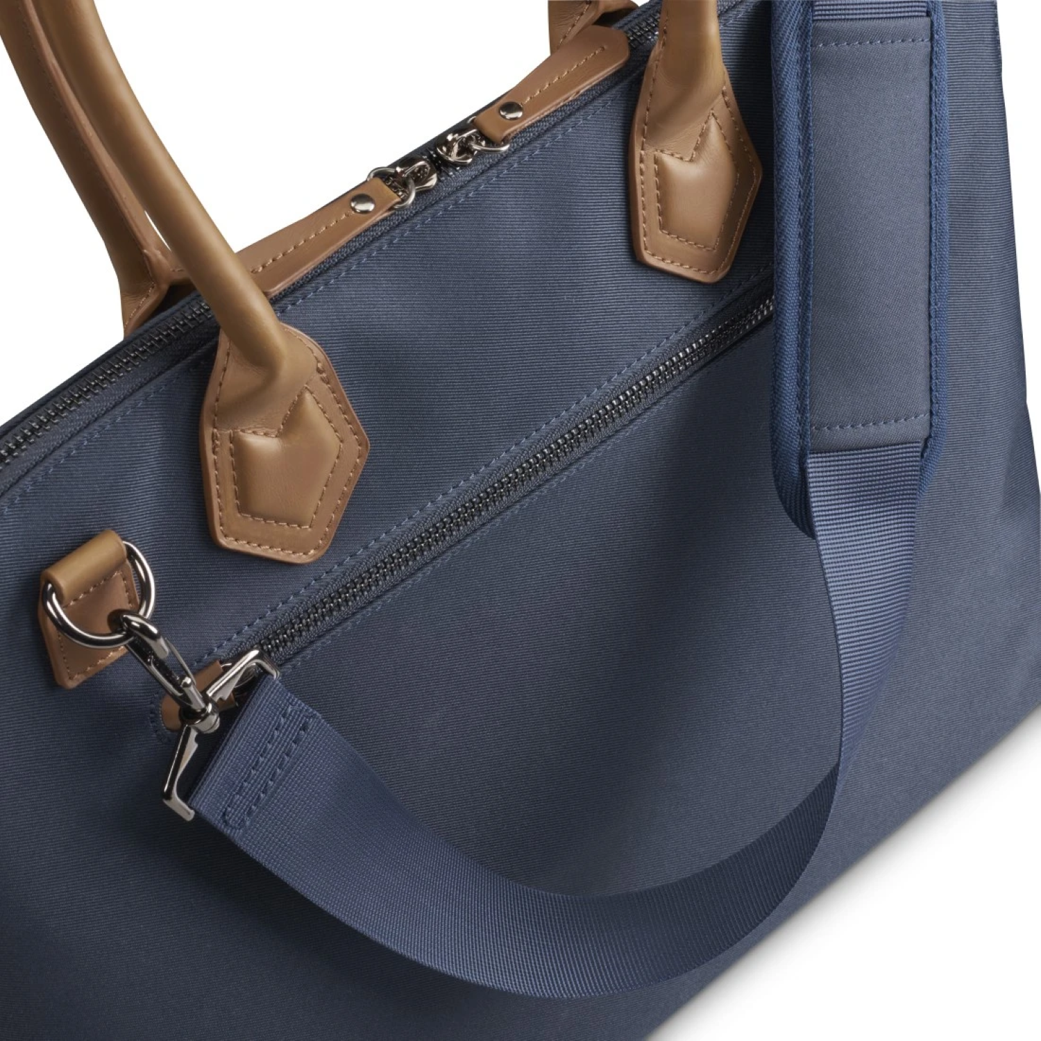 Nahaufnahme einer blauen Handtasche mit braunem Griff und blauem Schulterriemen. Ein silberner Verschluss ist sichtbar.