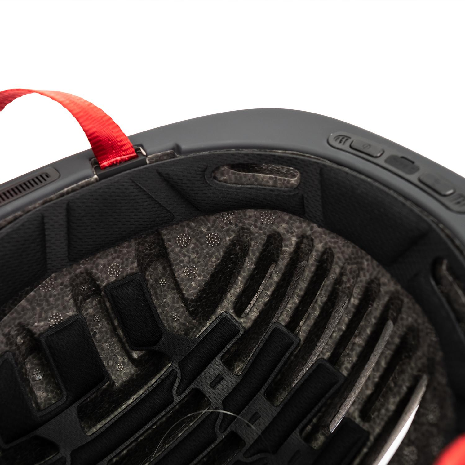 Interior de un casco de bicicleta, mostrando el acolchado, las correas y la correa roja que sale del casco.