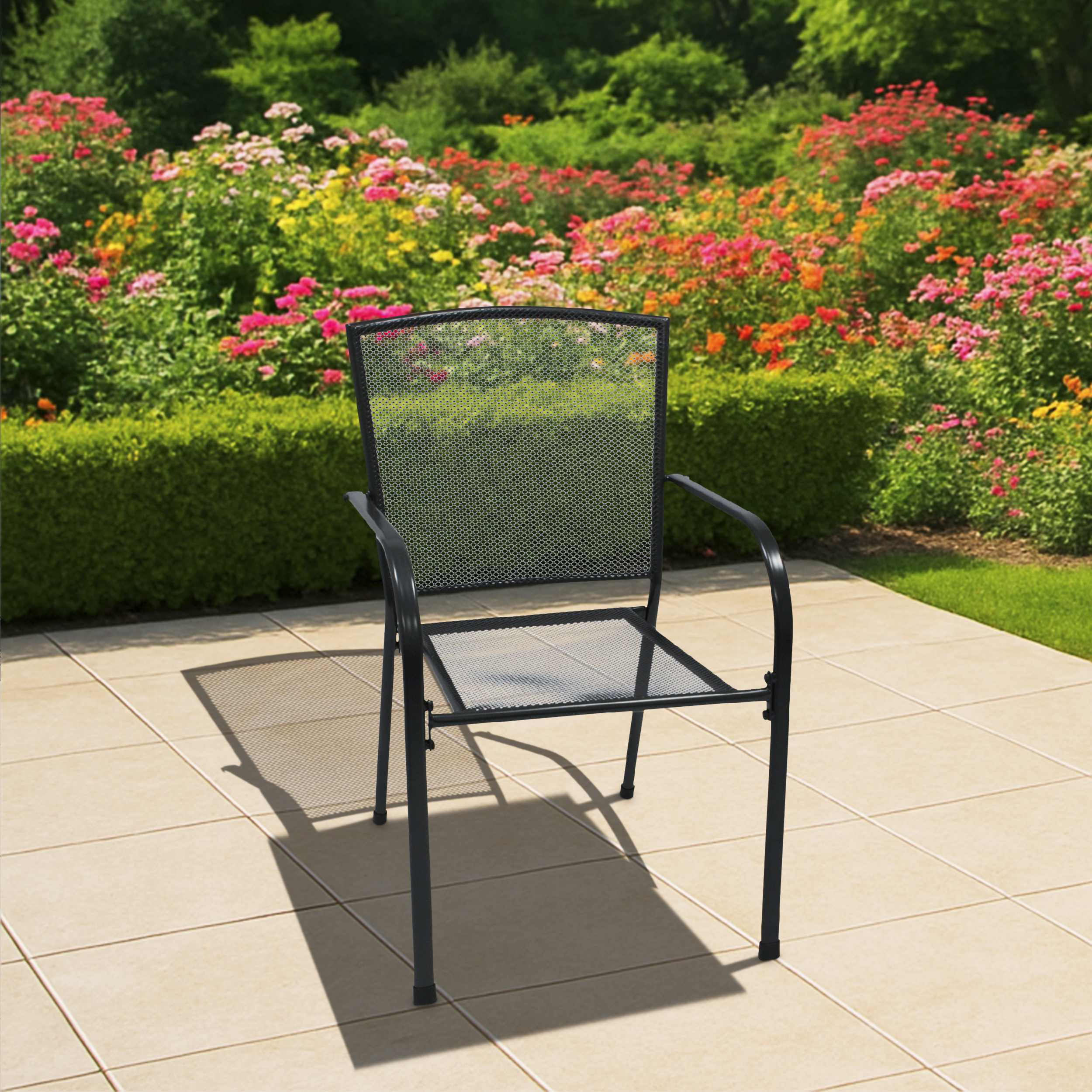 Ein schwarzer Metallstuhl mit Mesh-Sitz auf einer Terrasse, Blumen und Sträucher im Hintergrund, sonniger Tag.