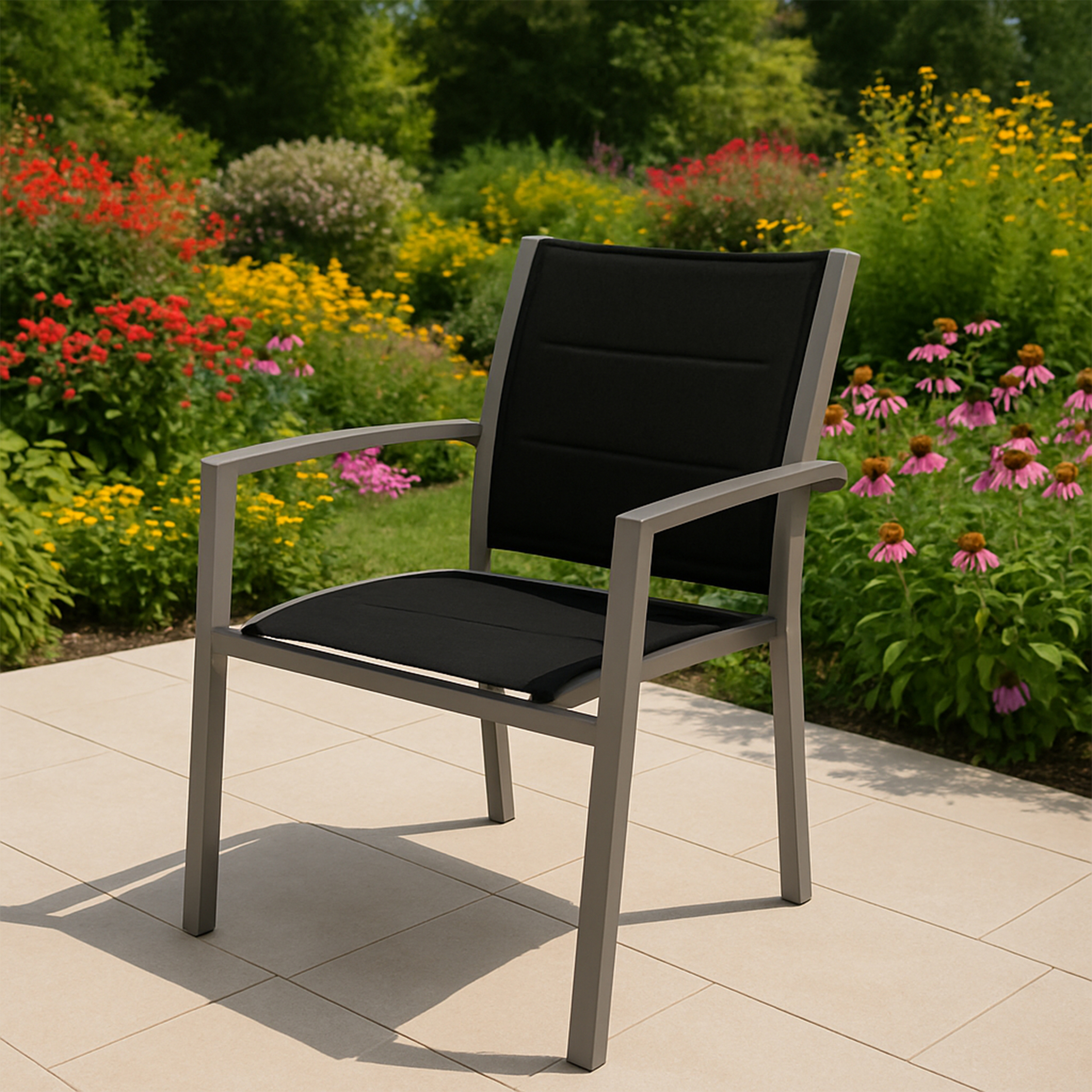 Gartenstuhl mit schwarzem Sitz und Rücken. Silberner Rahmen. Blumen im Hintergrund.