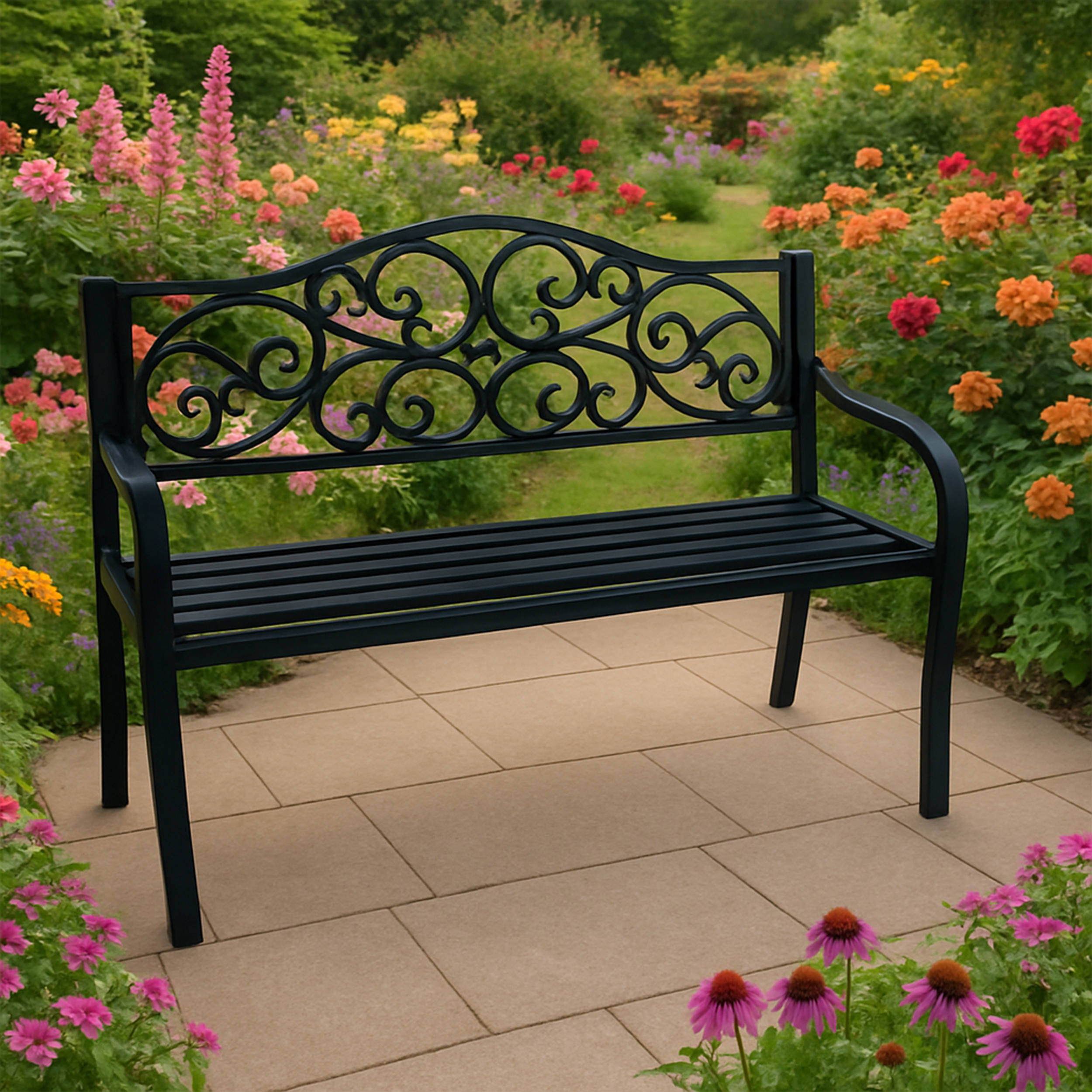 Schwarze Metallbank auf einer gefliesten Terrasse. Die Bank hat dekorative Wirbel auf der Rückseite. Blumen im Hintergrund.