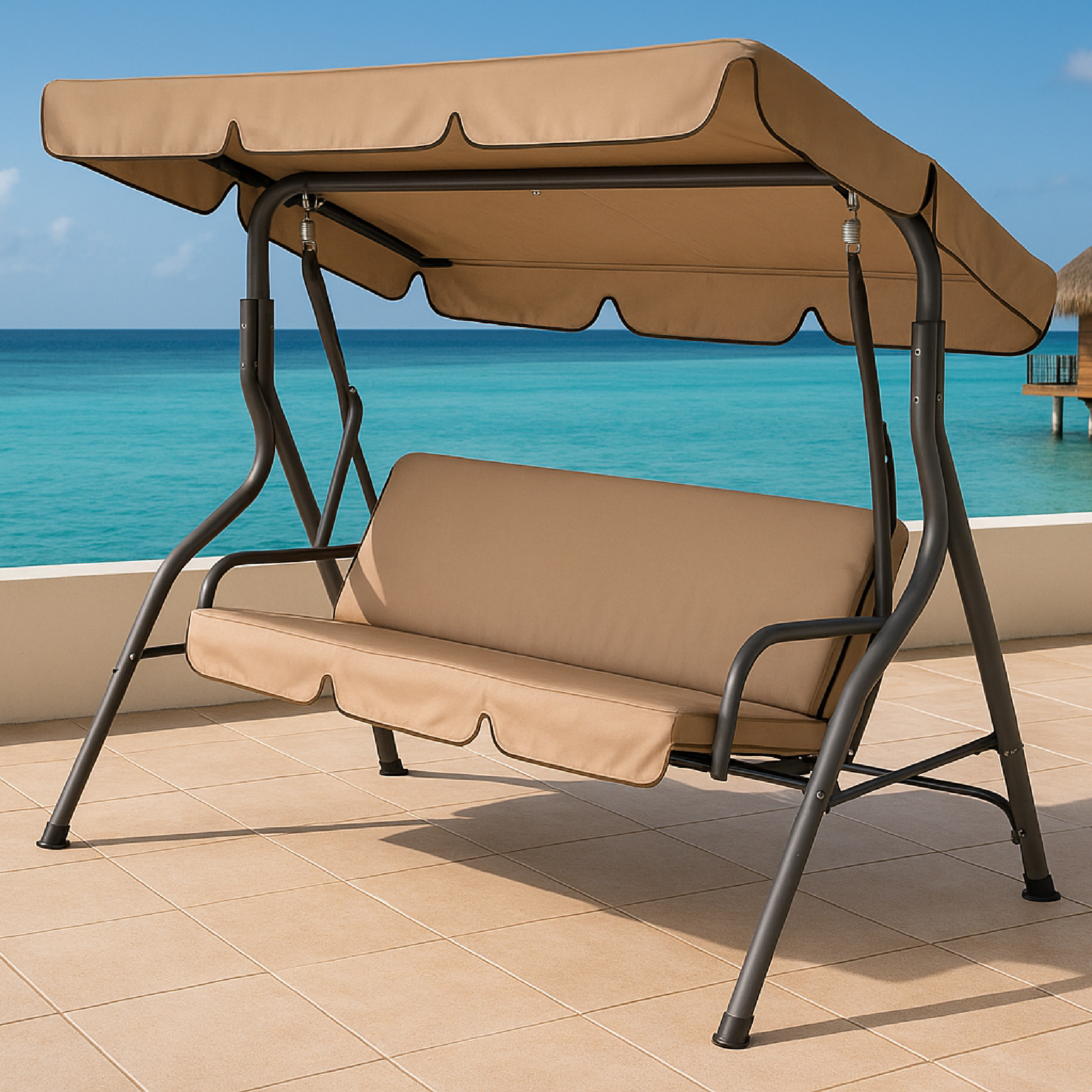 Beige Schaukel auf einer gefliesten Terrasse mit Blick auf ein türkisfarbenes Meer. Brauner Metallrahmen, beiger Baldachin und Kissen.
