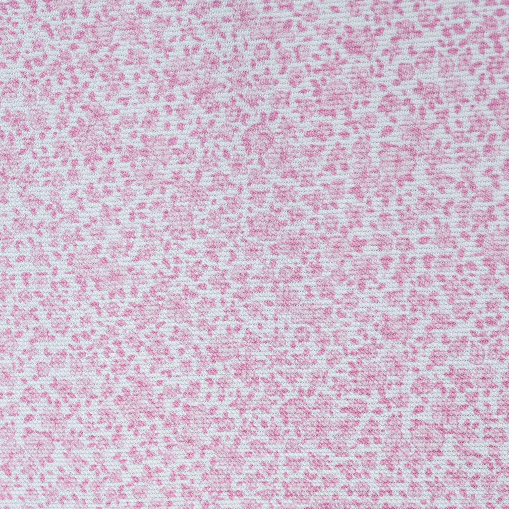 Primer plano de una tela floral rosa. El patrón presenta pequeñas flores rosa claro sobre un fondo rosa más claro.