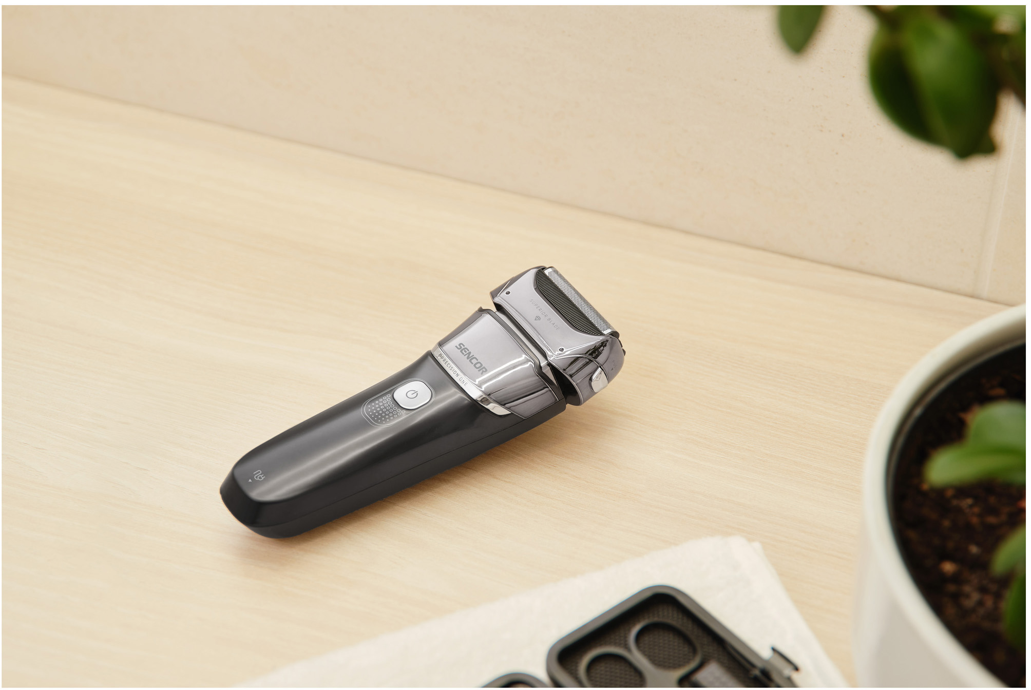 Un rasoio elettrico nero e argento su una superficie di legno con un asciugamano.