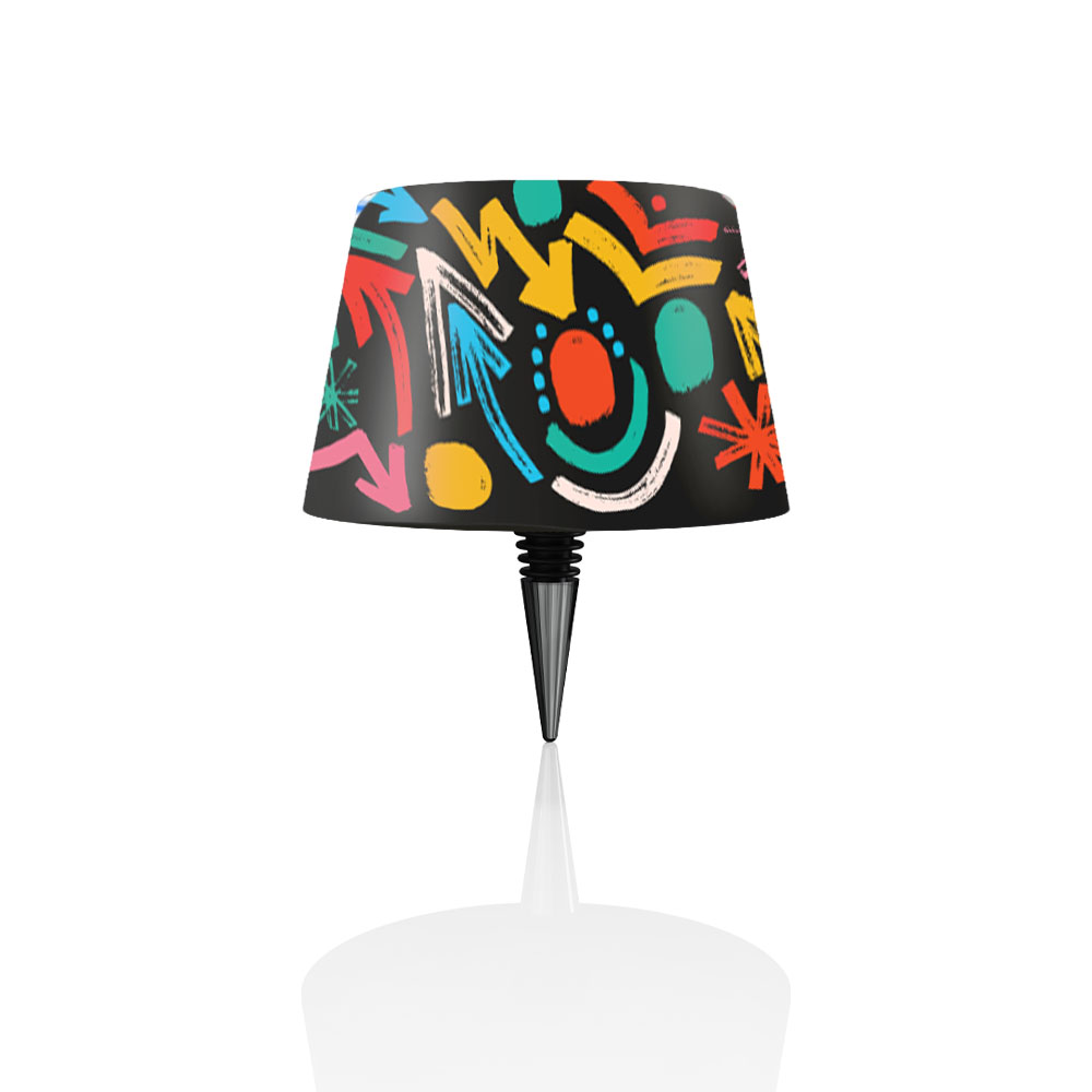Una lampada con paralume nero con frecce e forme colorate. La base è bianca.