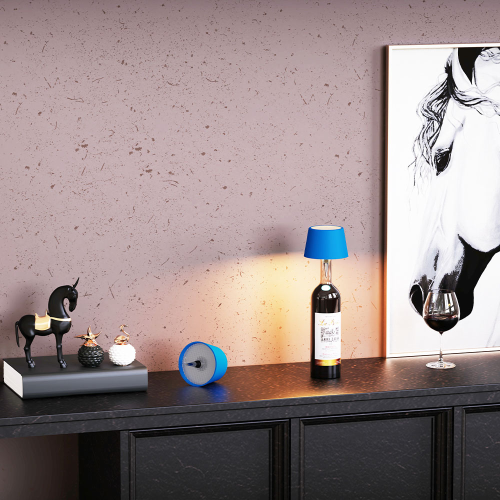Una lampada su un tavolo con decorazioni, bicchiere di vino e dipinto, con sfondo rosa.