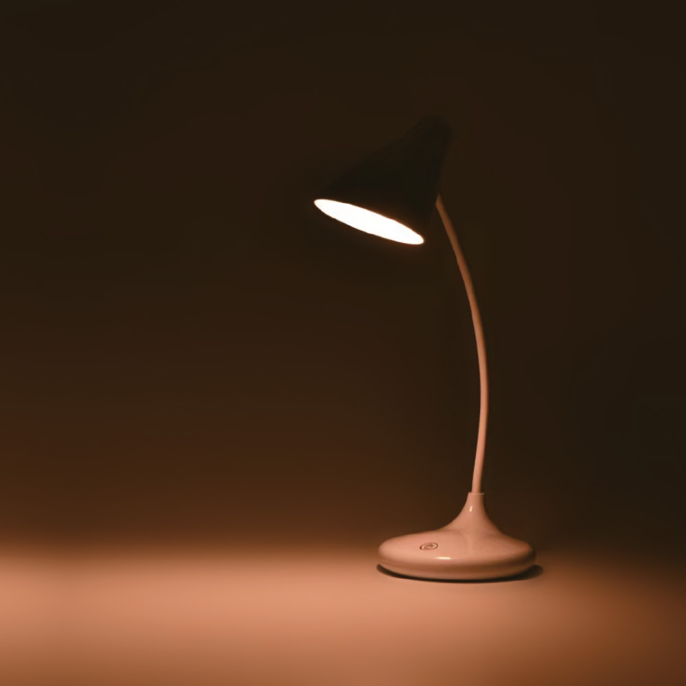 Una lampada bianca con paralume nero illumina una stanza buia. La lampada è accesa.