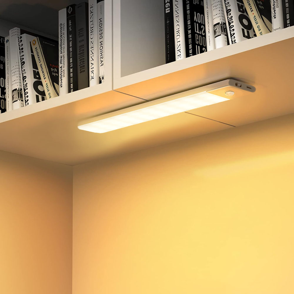 Una striscia luminosa a LED illuminata installata sotto uno scaffale, che emette luce calda.