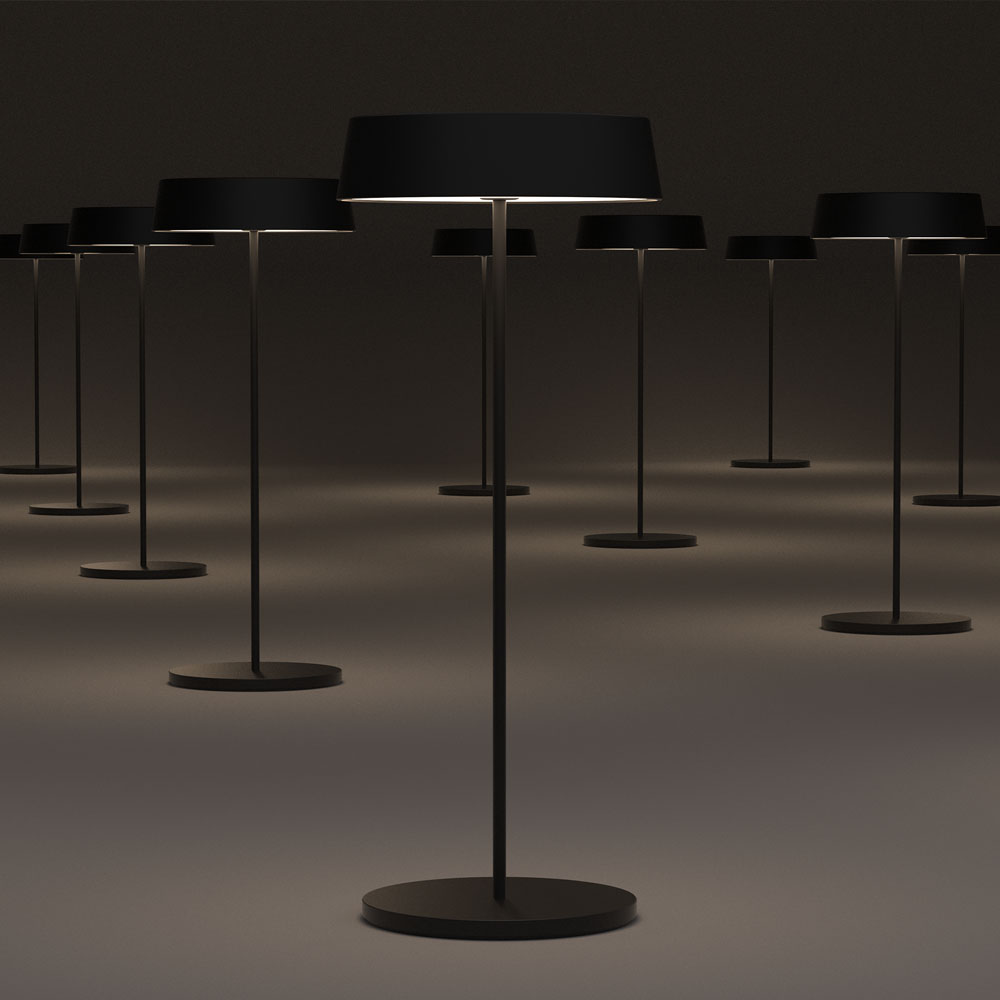 Una serie di lampade da terra nere con basi circolari e paralumi, collocate in una stanza buia.
