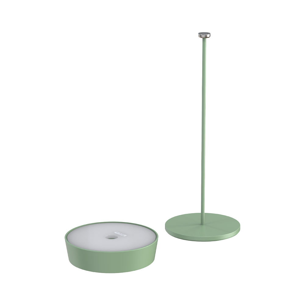 Una lampada verde con base rotonda e stelo staccato. Sfondo bianco.