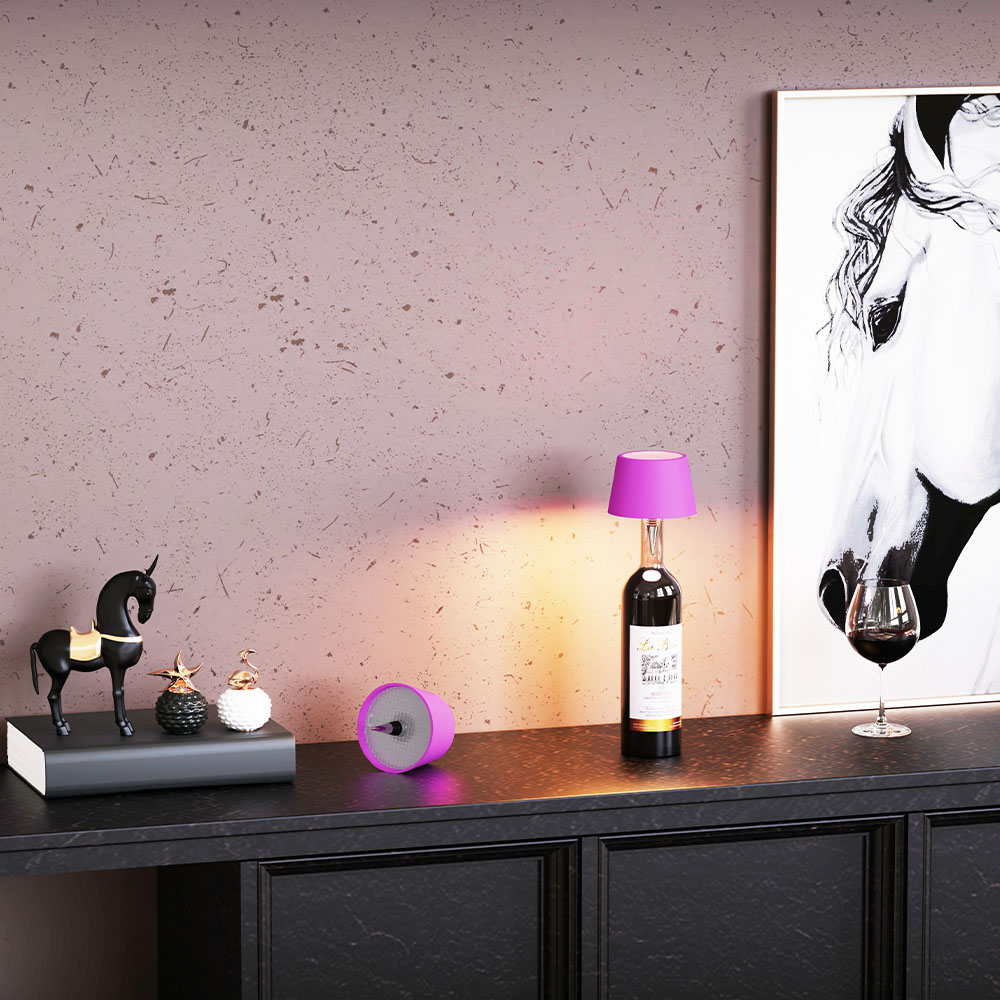 Un mobile nero con decorazioni e una lampada fatta con una bottiglia di vino. Un bicchiere di vino sopra.