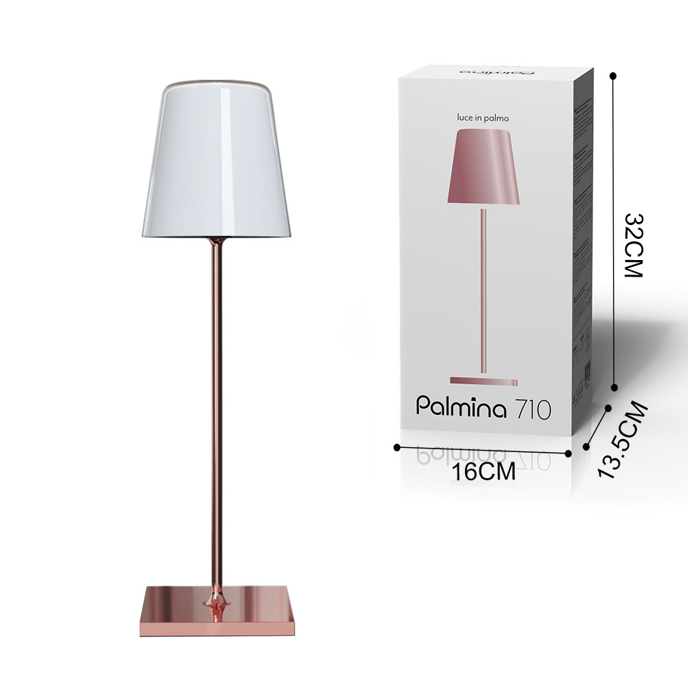 Una lampada con paralume bianco, stelo oro rosa e base quadrata, con la sua scatola.