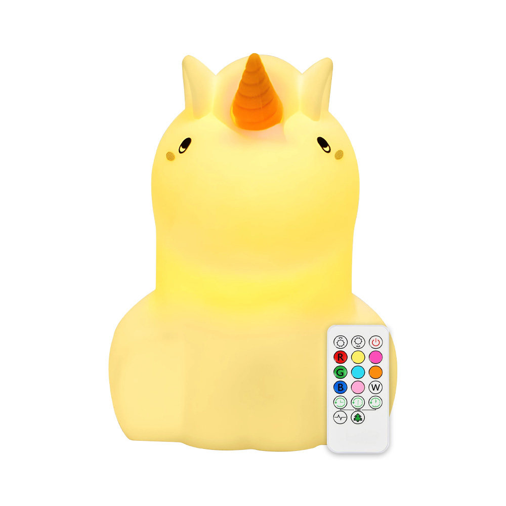 Lampada a forma di unicorno giallo con telecomando. È illuminata. Sfondo bianco.