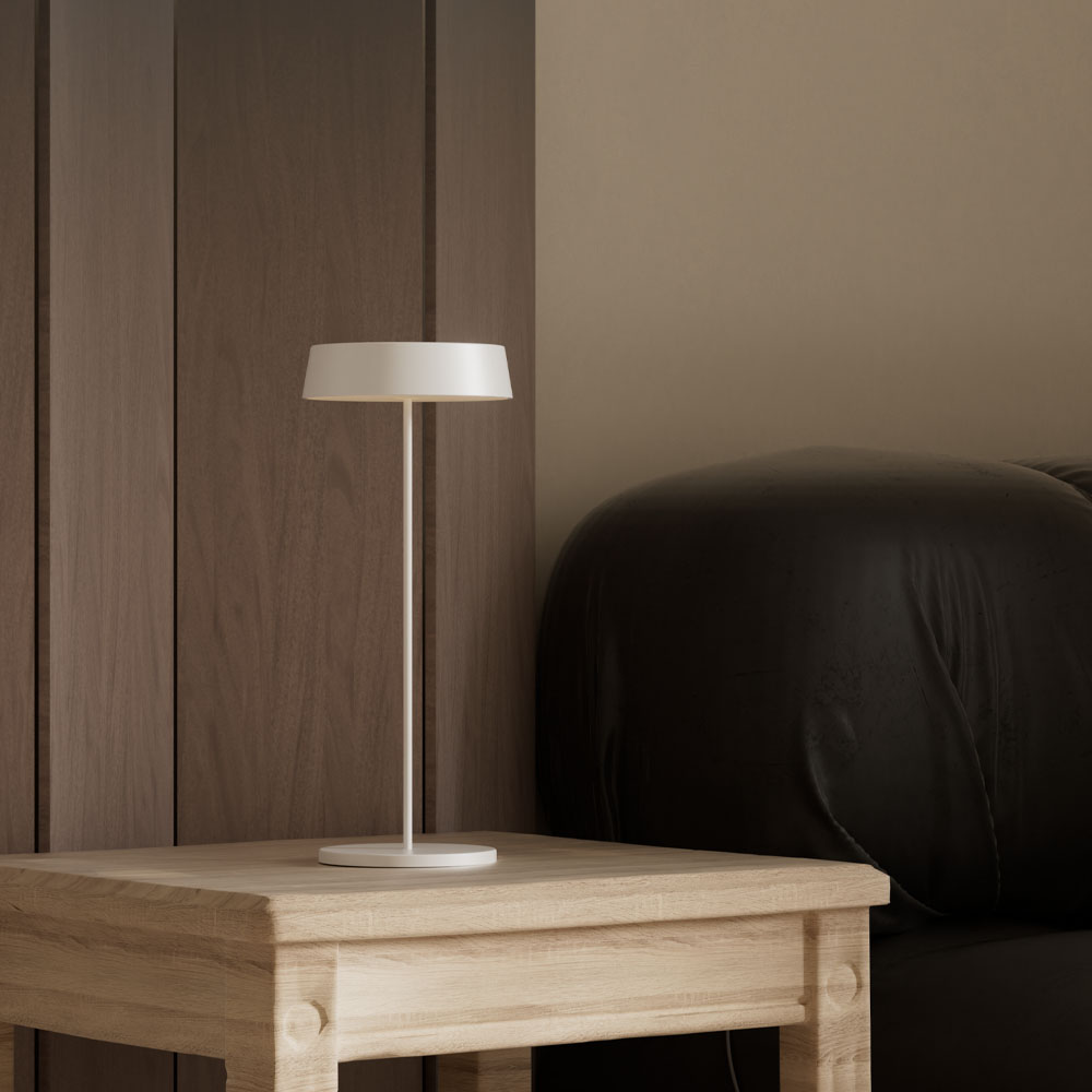 Una lampada su un comodino di legno accanto a un letto. Lo sfondo è un muro di legno.