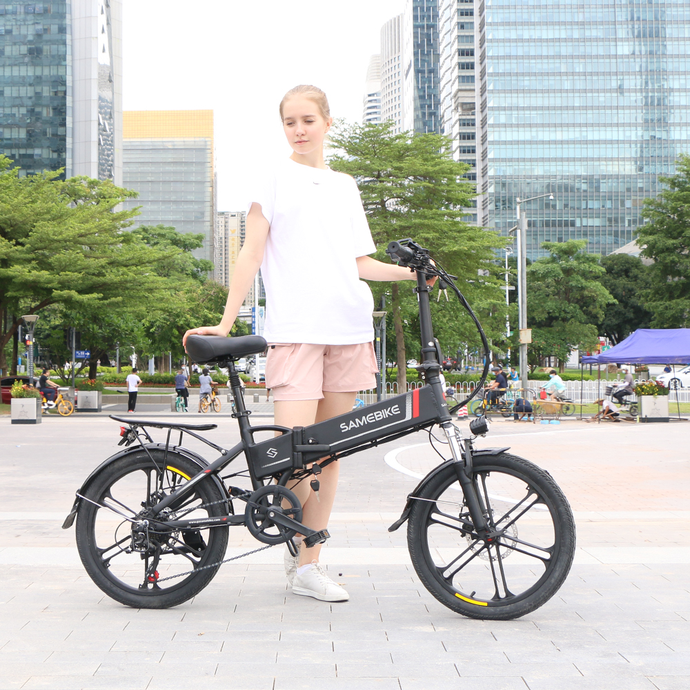 Frau steht neben einem schwarzen Samebike E-Bike. Gebäude im Hintergrund.