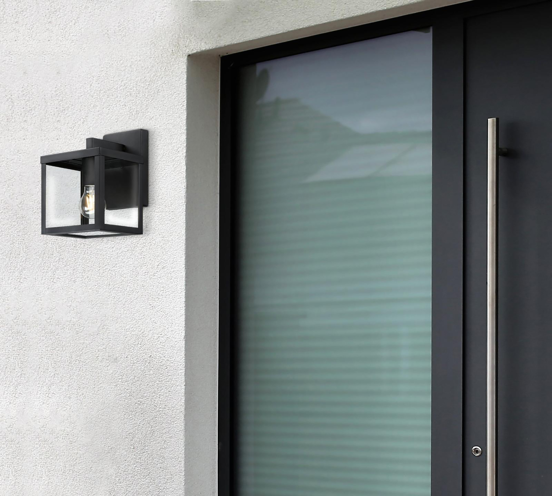 Schwarze Wandleuchte an einer strukturierten weißen Wand. Rechts eine dunkle Tür mit Glas und einem silbernen Griff.