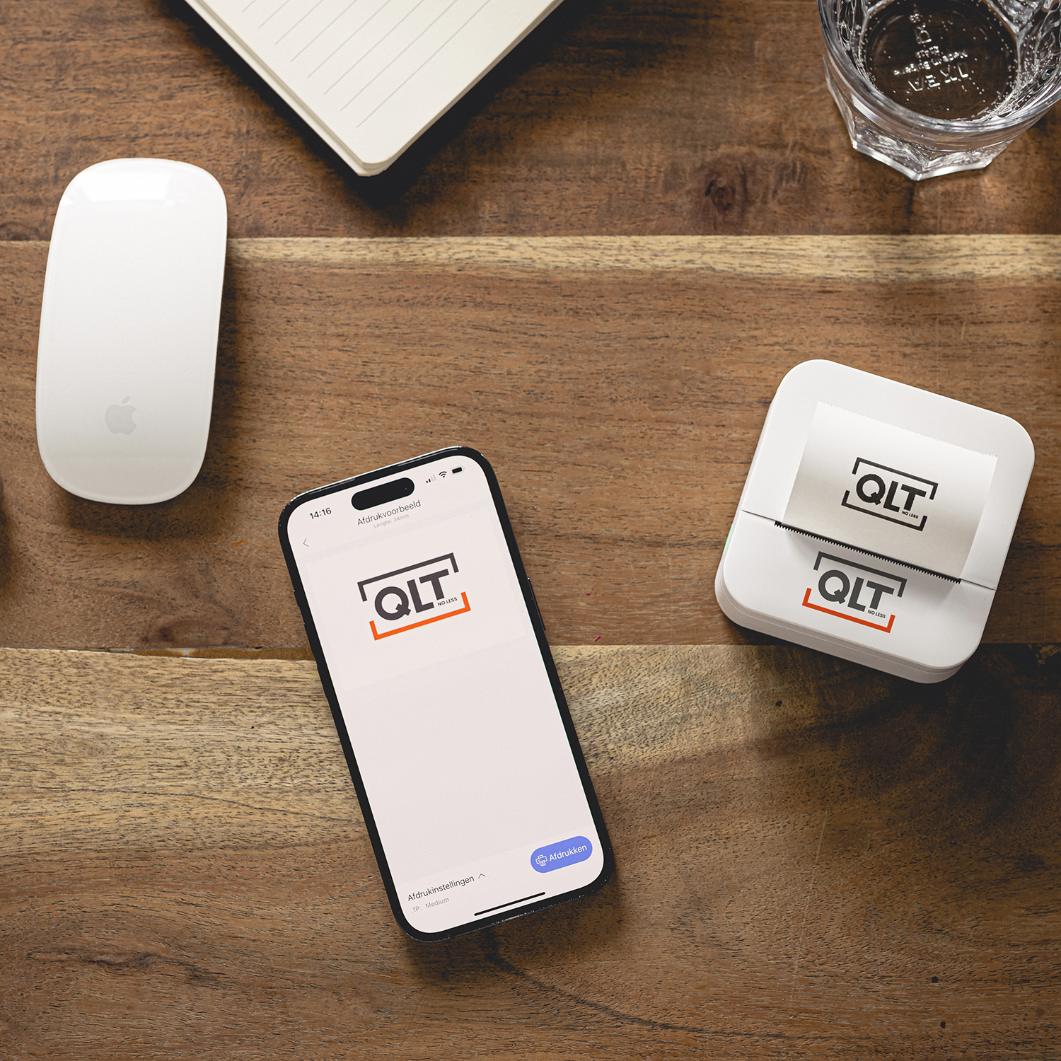 A wooden desk with a white mouse, a phone, and a printer. The phone screen shows a logo. The desk is wooden.