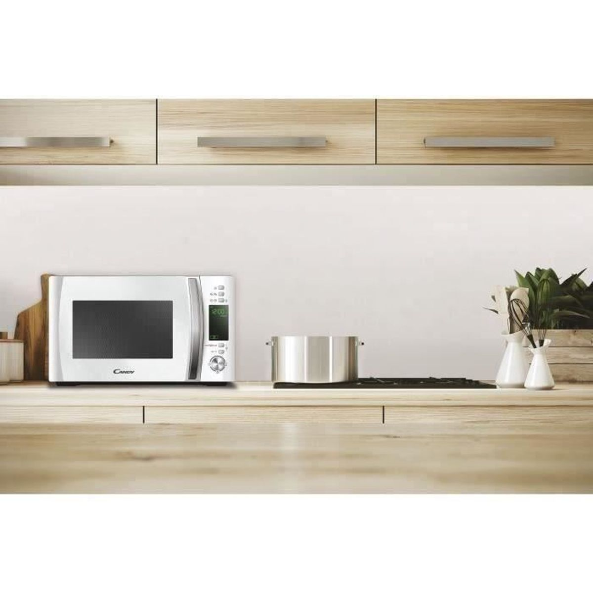 Un forno a microonde bianco su un bancone di legno in cucina, con una pentola e piante.