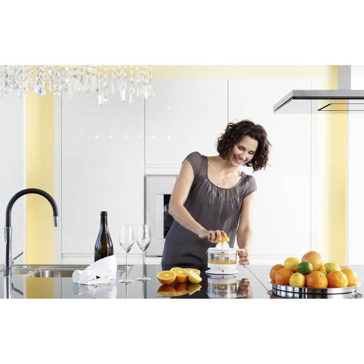 Donna che spremi arance in cucina. Frutta su un piatto.