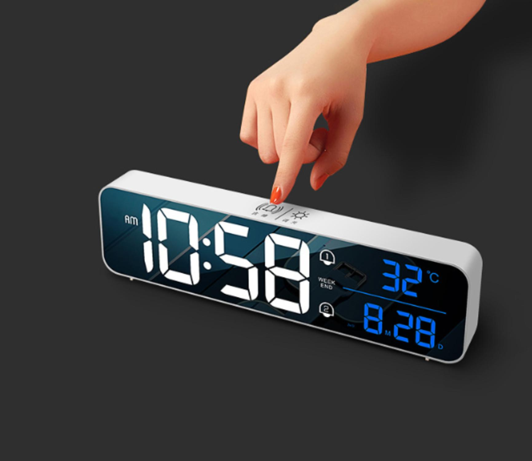 Eine Hand drückt die Schlummertaste auf einer Digitaluhr. Die Uhr zeigt 10:58 Uhr an, mit Datum und Temperatur.