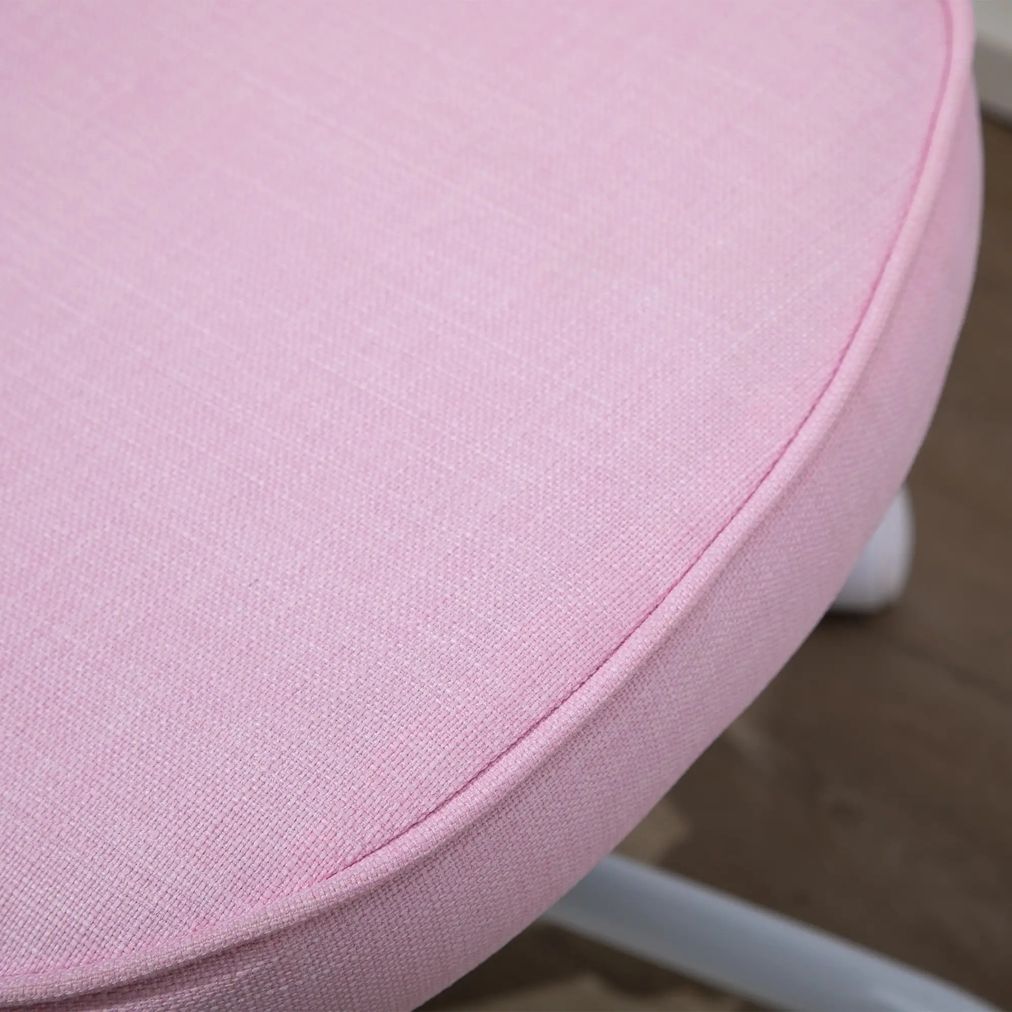 Nahaufnahme eines rosa Stuhlsitzes. Der Sitz ist rund und hat einen hellrosa Stoff. Der Hintergrund ist unscharf.