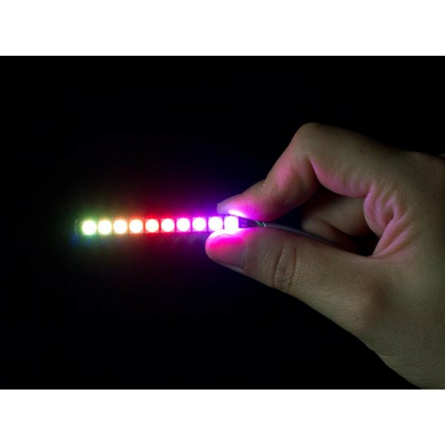 Hand, die einen Streifen LEDs hält, die in mehreren Farben leuchten. Schwarzer Hintergrund.