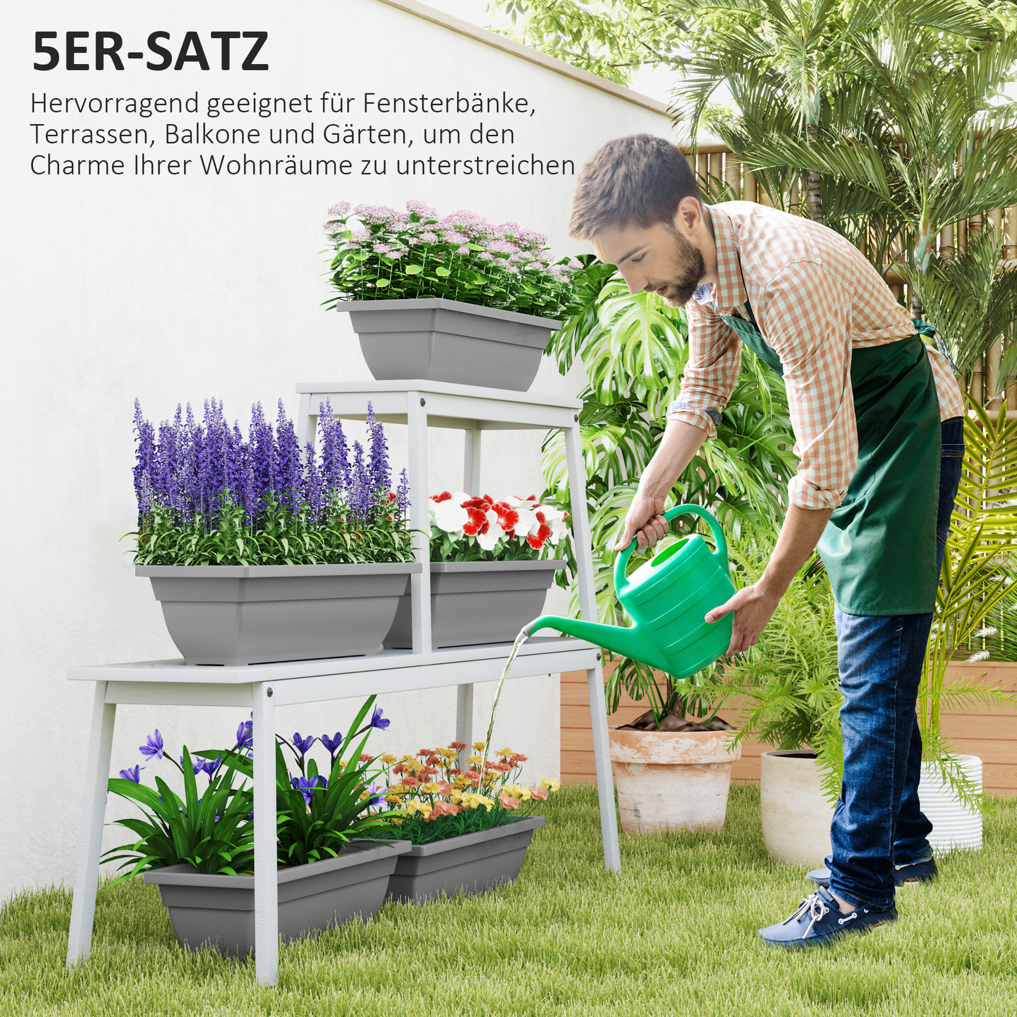 Ein Mann gießt Pflanzen in Pflanzkästen auf einem weißen Regal in einem Garten mit weißer Wand.