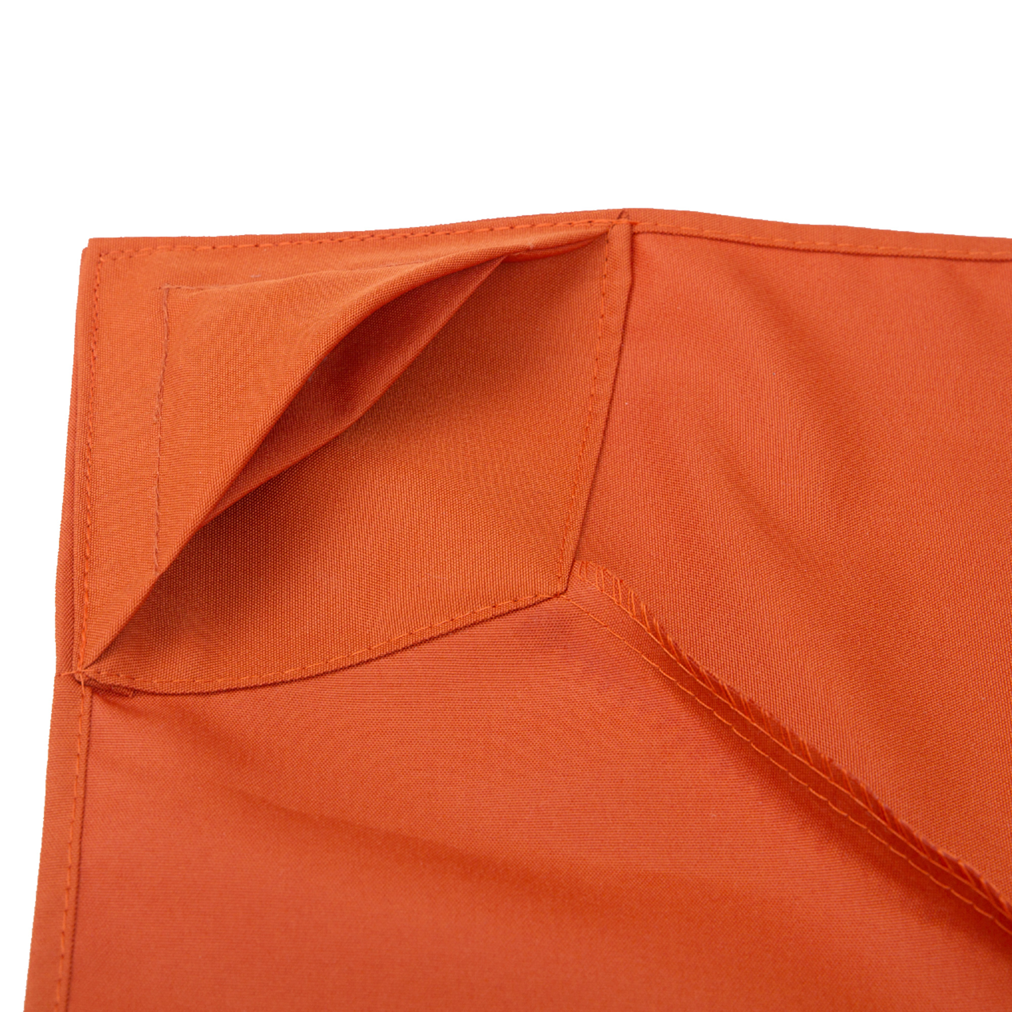 Nahaufnahme eines orangefarbenen Stoffes mit taschenartiger Falte und genähten Kanten. Der Stoff wirkt flach.