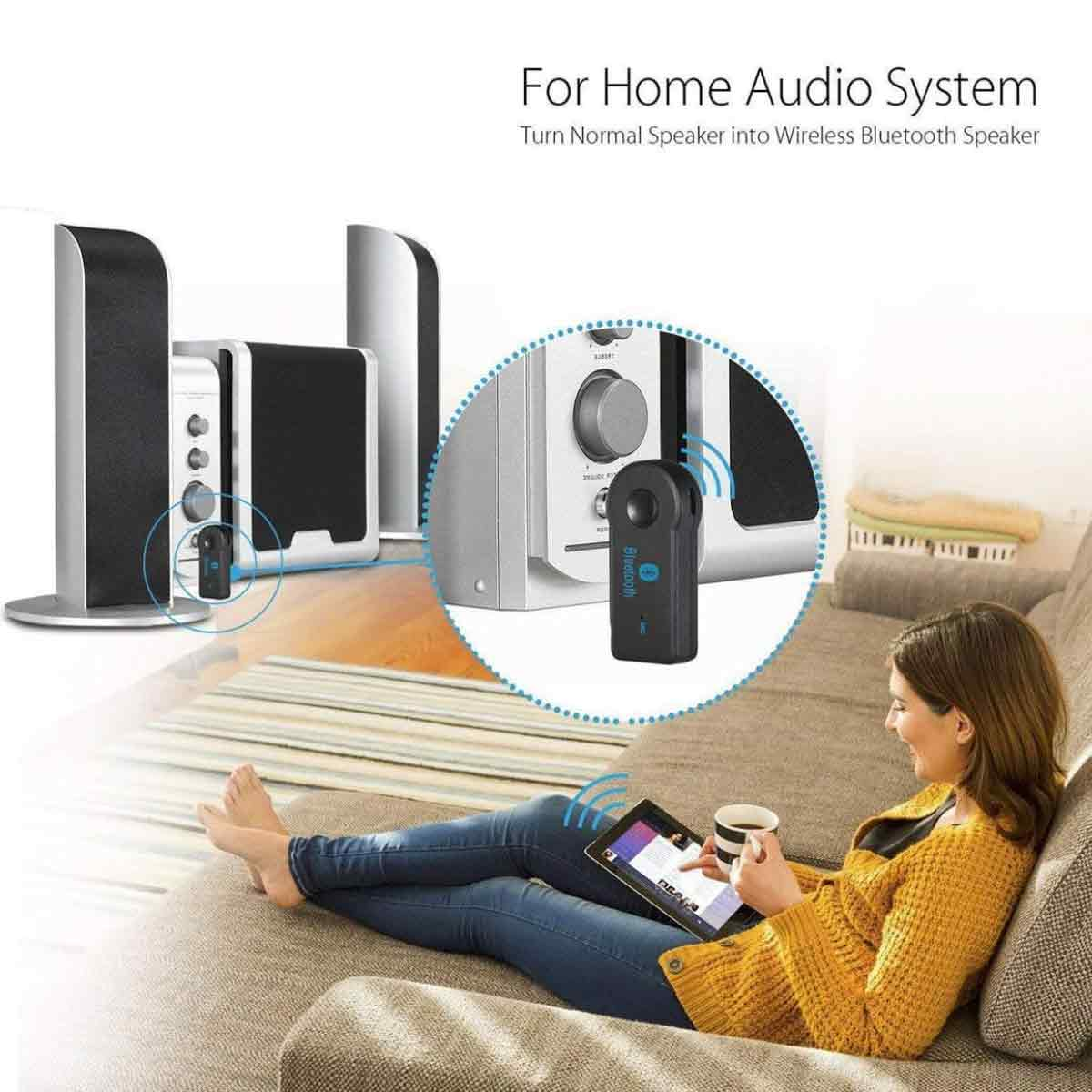 Eine Frau sitzt auf einem Sofa, benutzt ein Tablet und hält eine Tasse. Ein Bluetooth-Adapter ist mit Lautsprechern verbunden.
