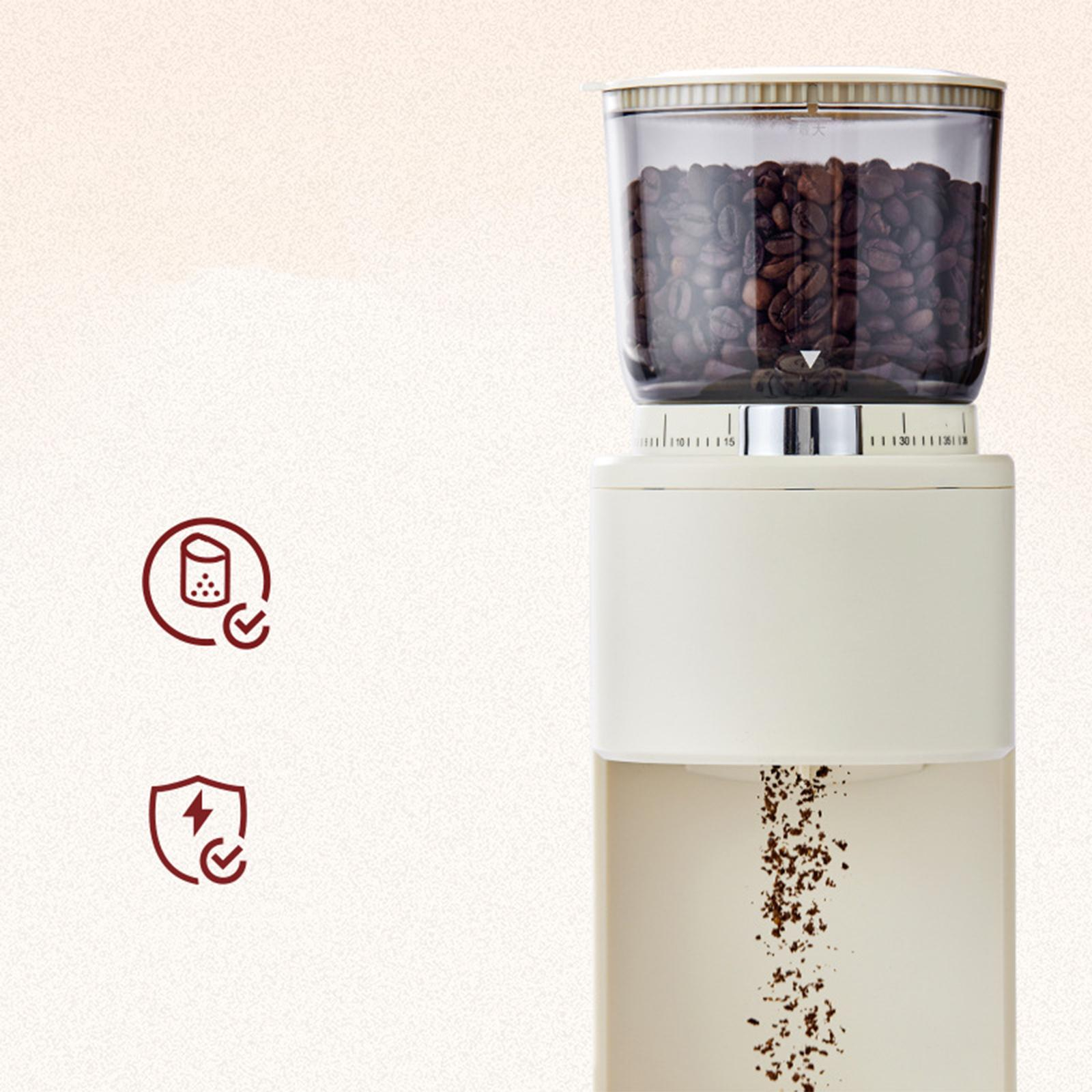 Eine cremefarbene Kaffeemühle mit Kaffeebohnen im oberen Behälter und Mahlgut, das unten herauskommt.