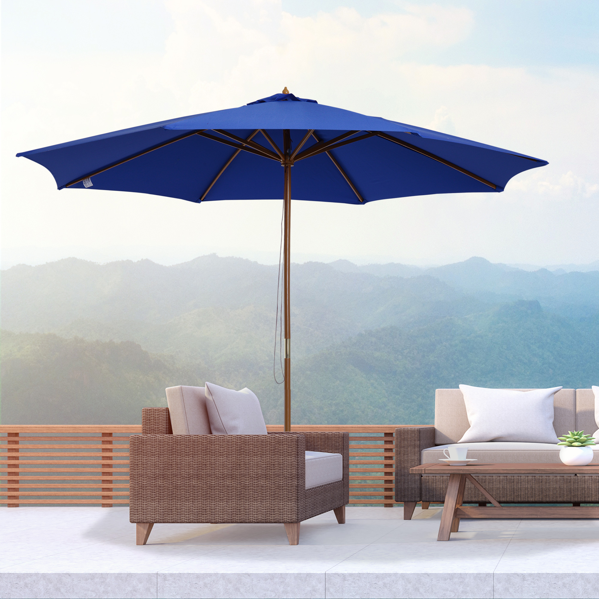 Außenbereich mit einem großen blauen Sonnenschirm, einem Korbmöbel-Sofa und -Sessel sowie Bergblick.