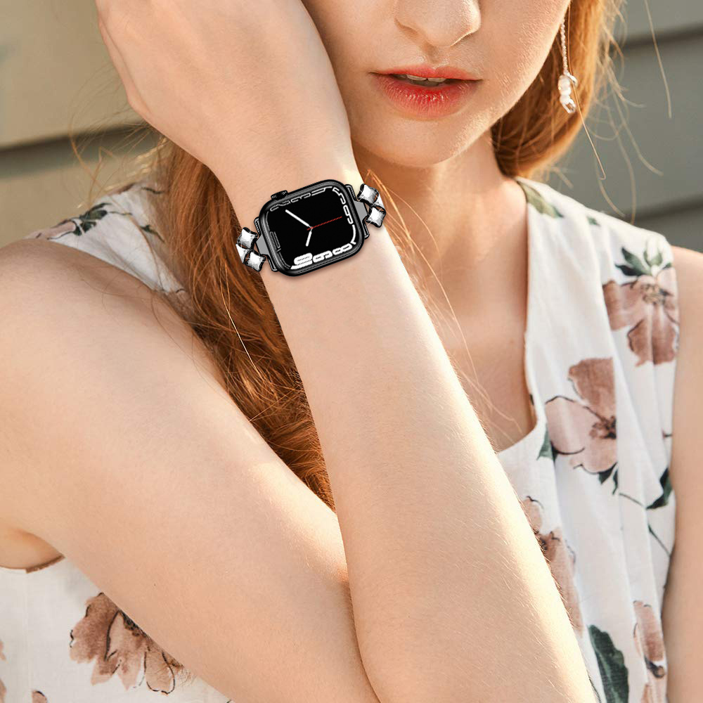 Eine Frau trägt eine schwarze Smartwatch mit einem Kristallarmband am Handgelenk.