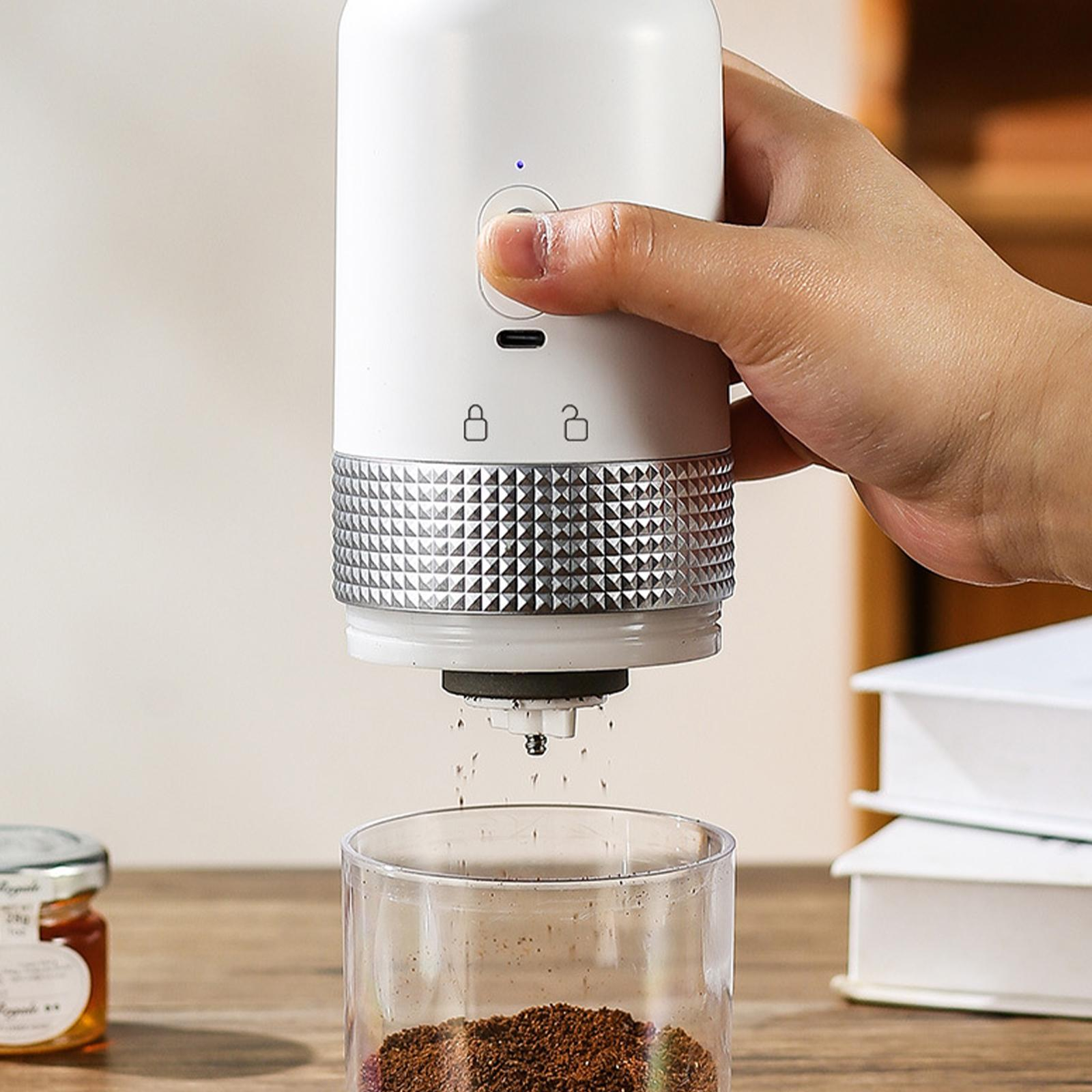 Eine Hand drückt auf einen Knopf eines weißen Kaffeezubereiters und gibt Kaffeepulver in einen transparenten Behälter aus.
