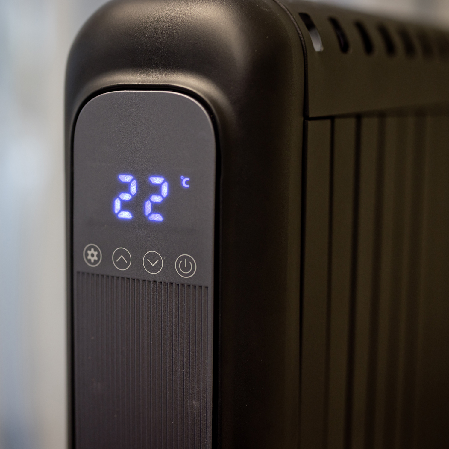 A close-up of a black heater with a digital display showing '22°C' and control buttons.