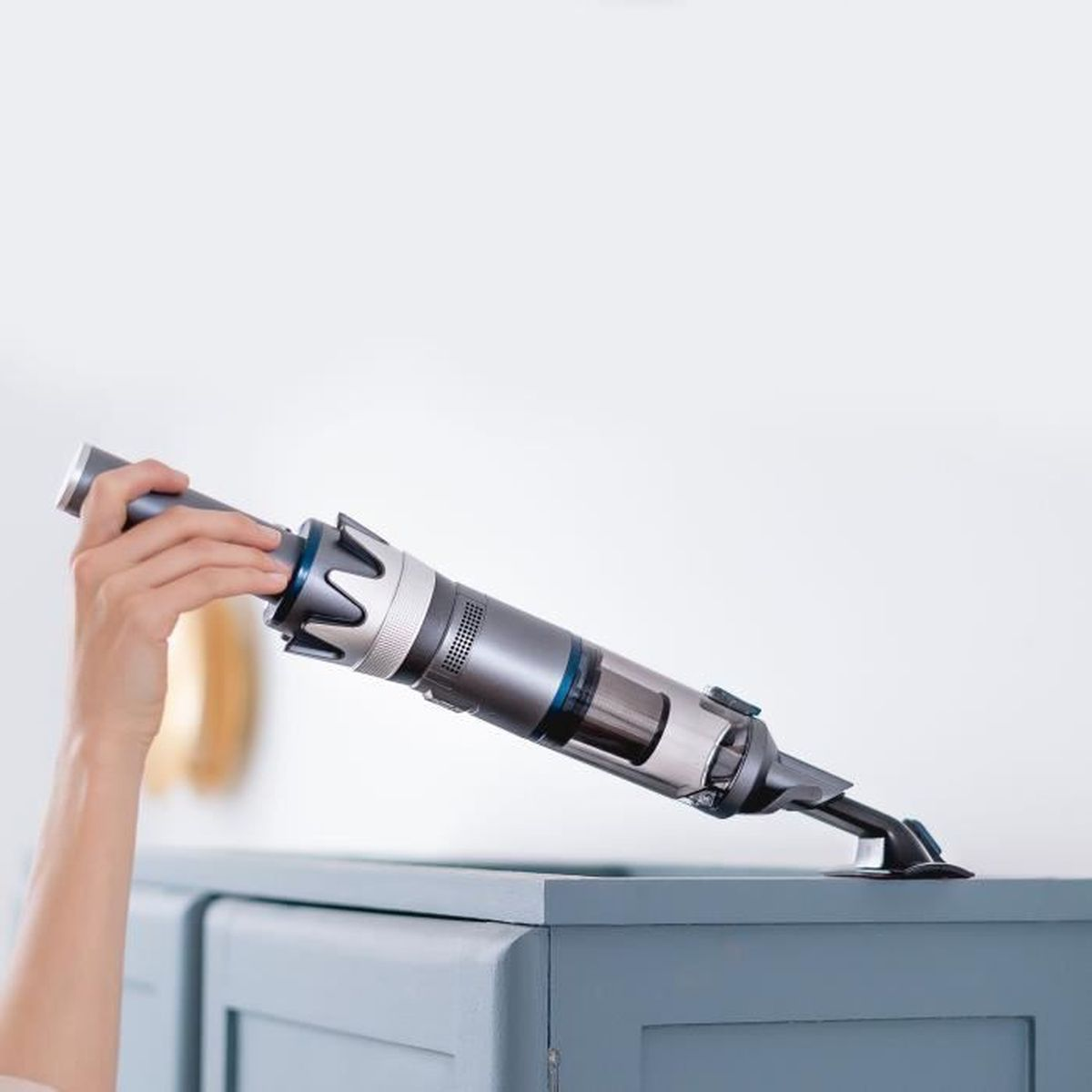 Ein Staubsauger wird an einem Schrank verwendet. Grau und Silber. Weißer Hintergrund.