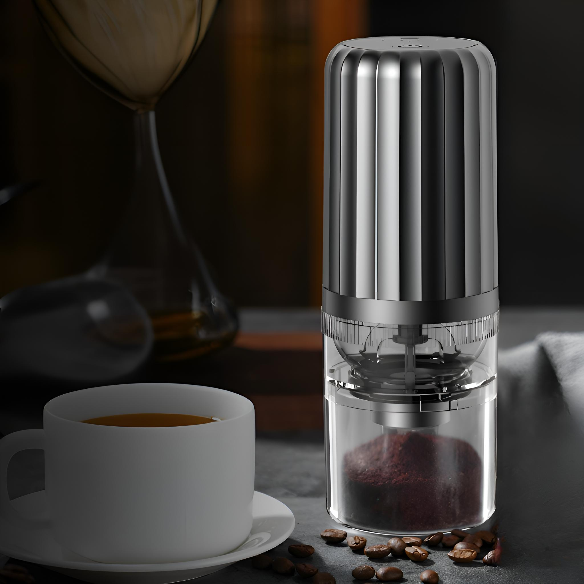Ein elektrischer Kaffeemühle aus Edelstahl auf einem Tisch, in der Nähe einer Tasse Kaffee und Kaffeebohnen. Dunkler Hintergrund.