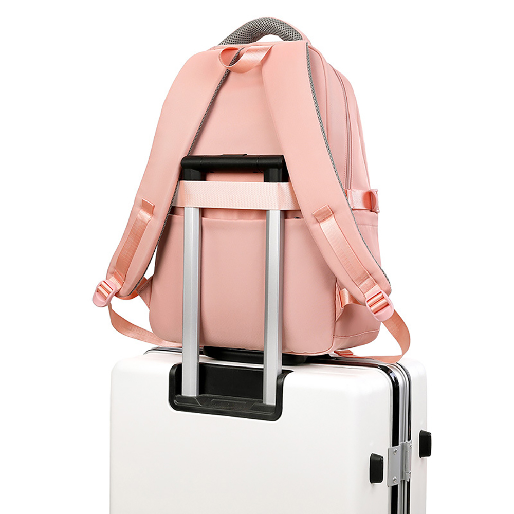 Ein rosafarbener Rucksack sitzt auf einem weißen Koffer mit ausgezogenem Griff vor einem weißen Hintergrund.