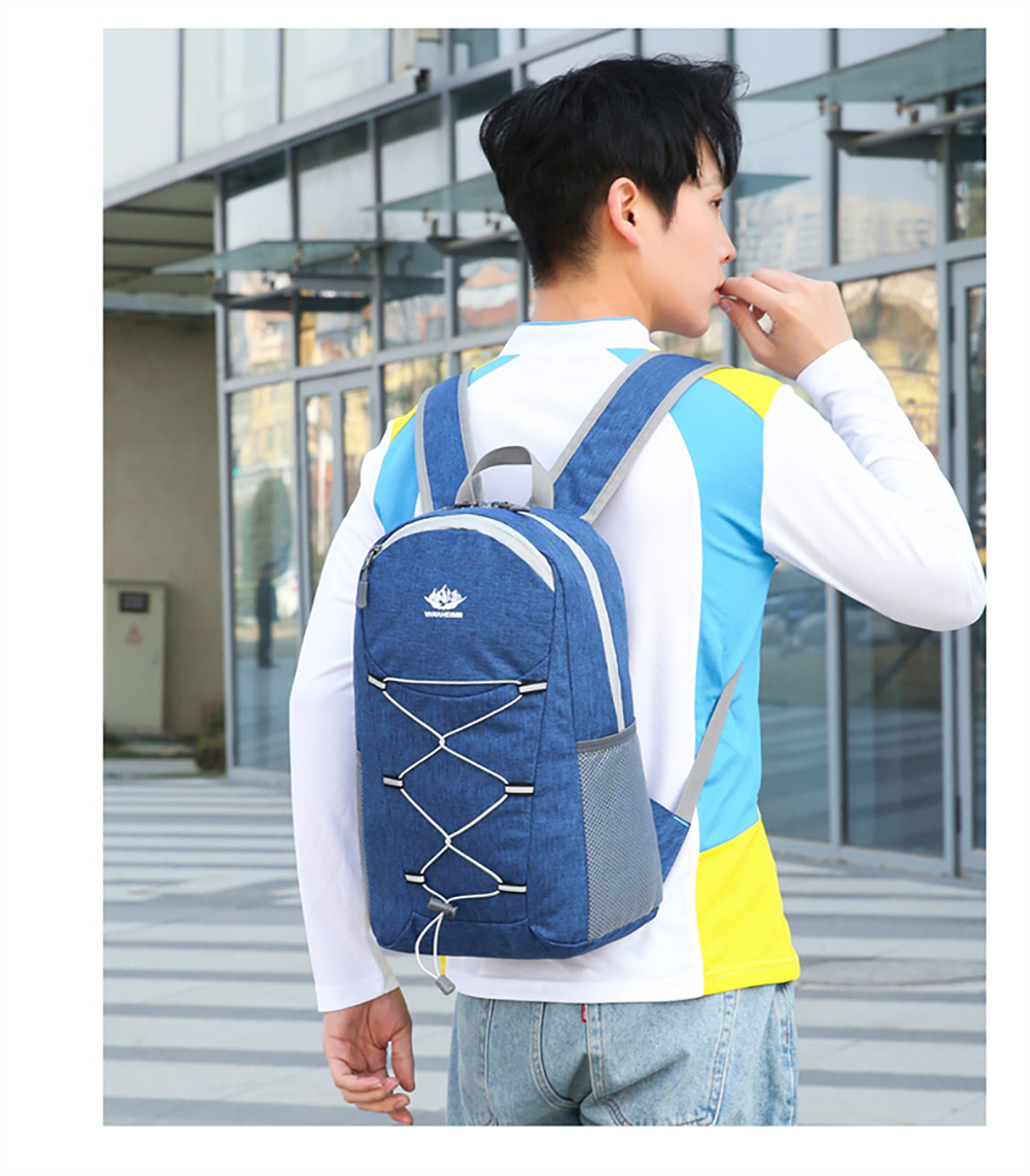 Ein Mann in einem weißen und blauen Hemd trägt einen blauen Rucksack mit weißen Bungee-Seilen und steht vor einem Gebäude.