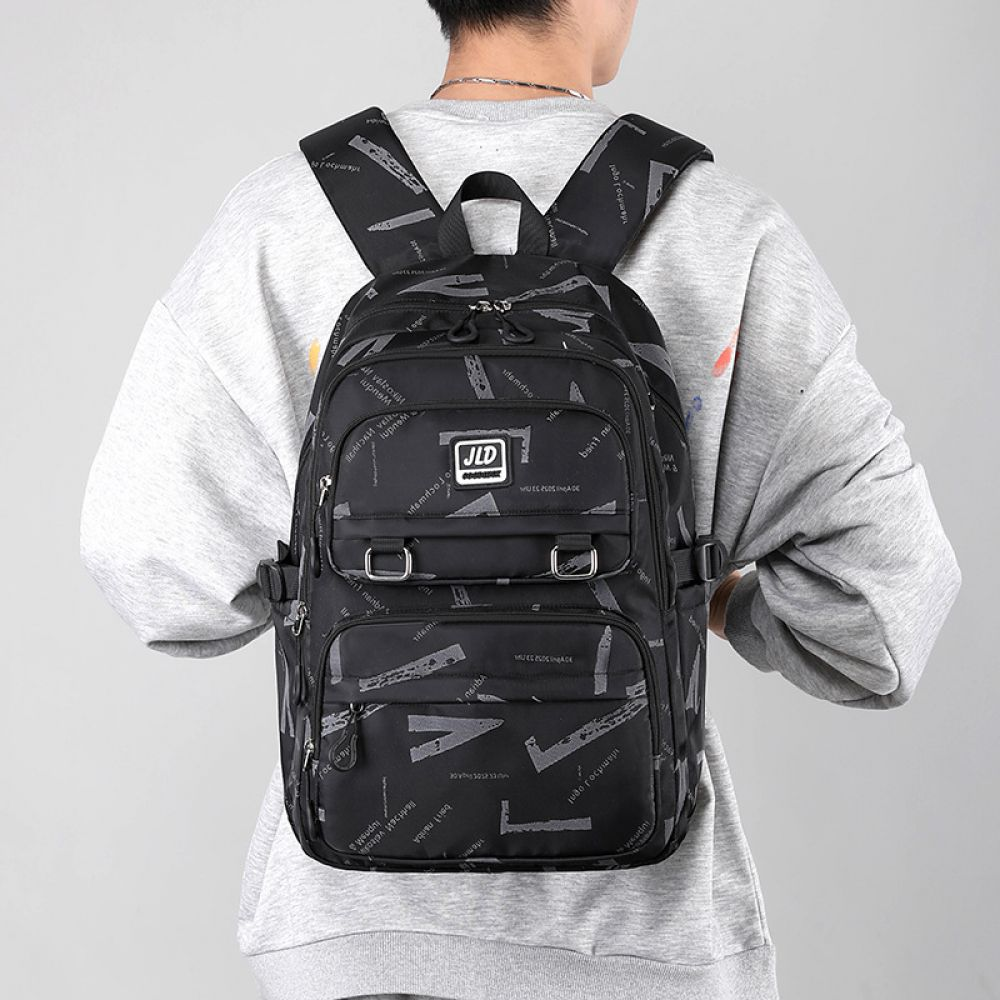 Eine Person trägt einen grauen Pullover und einen schwarzen Rucksack mit Buchstaben bedeckt.