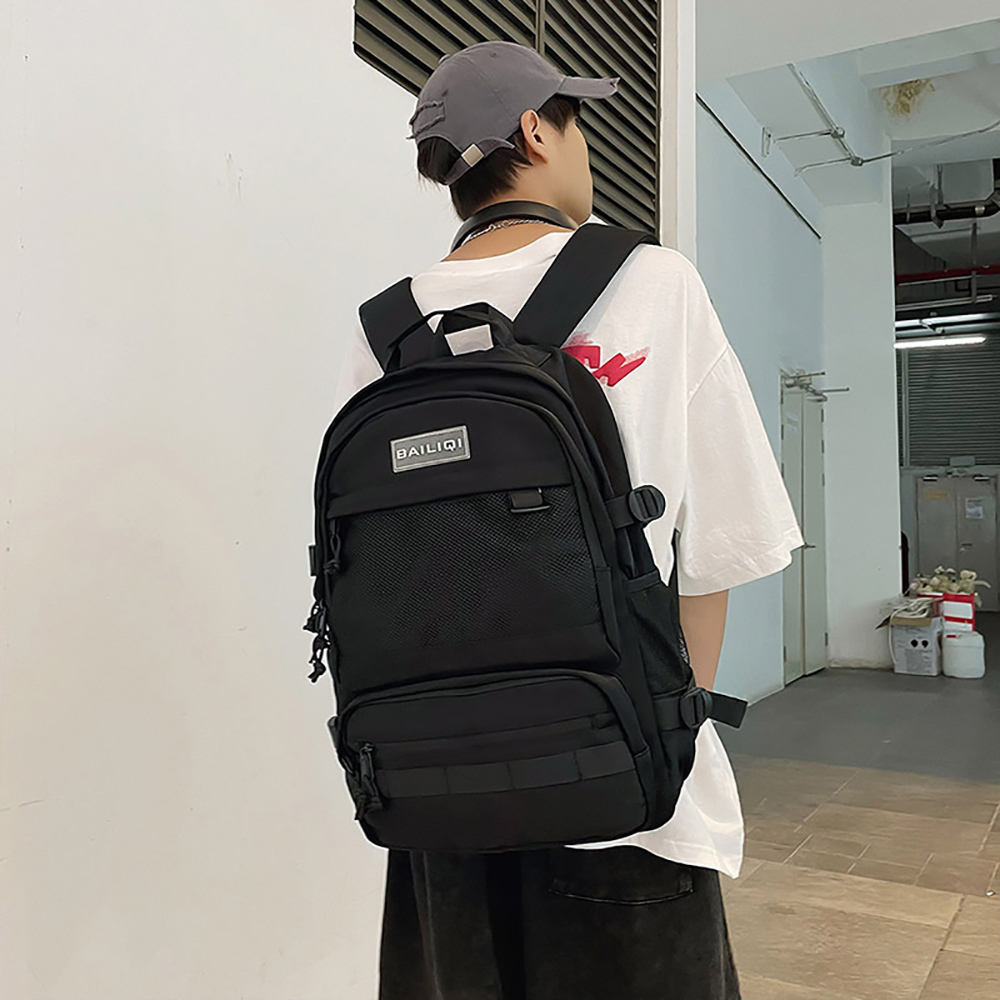 Eine Person trägt ein weißes T-Shirt und einen schwarzen Rucksack. Der Rucksack hat mehrere Taschen und ein Logo.