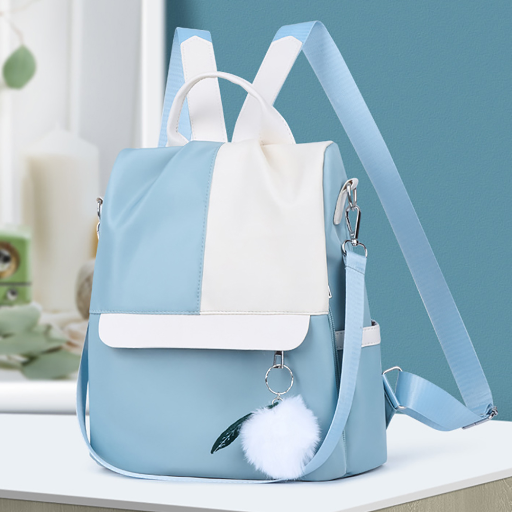 Ein blau-weißer Rucksack mit einem flauschigen Ball. Er hat Träger und einen oberen Griff.