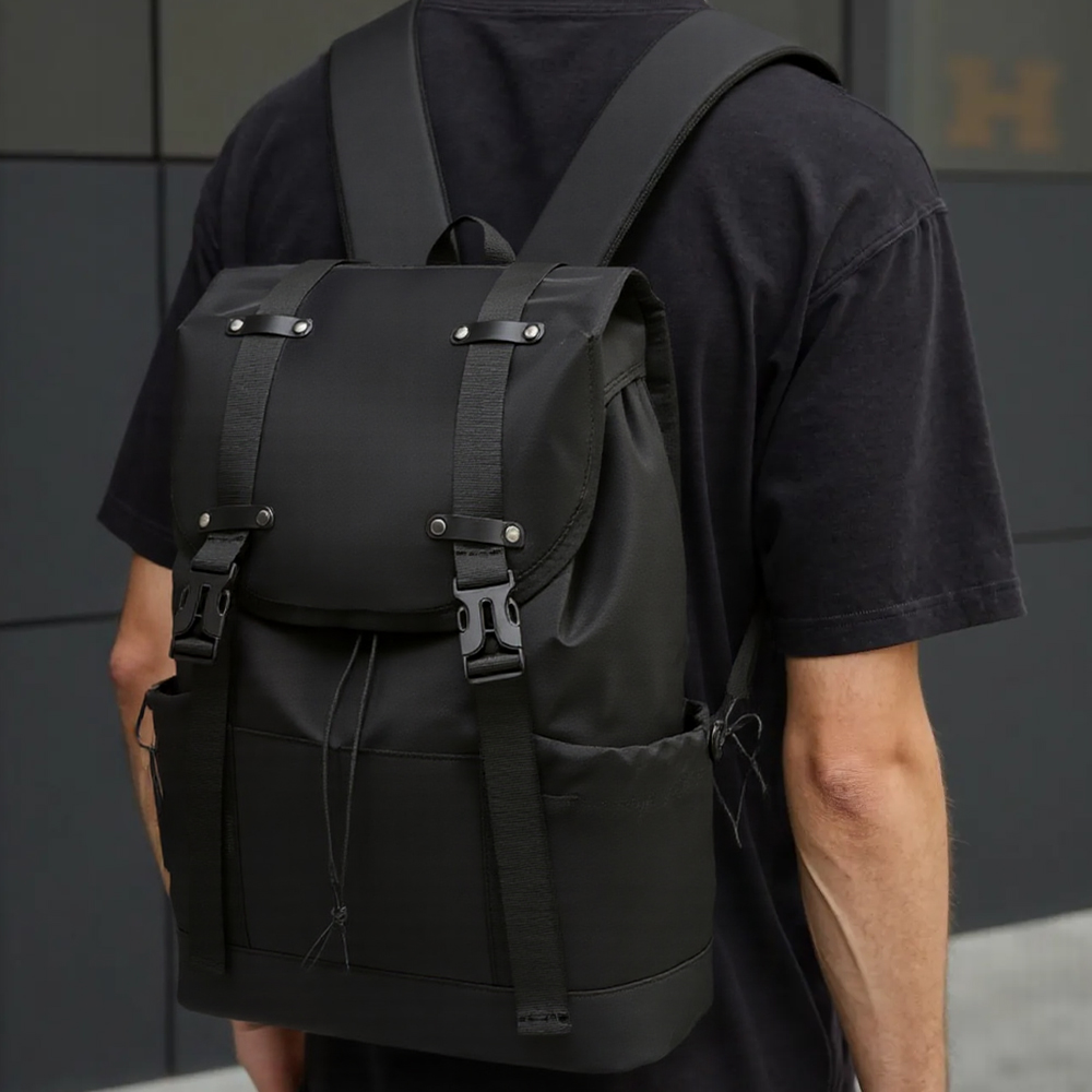 Eine Person trägt einen schwarzen Rucksack. Der Rucksack hat Träger, Schnallen und einen Kordelzugverschluss.