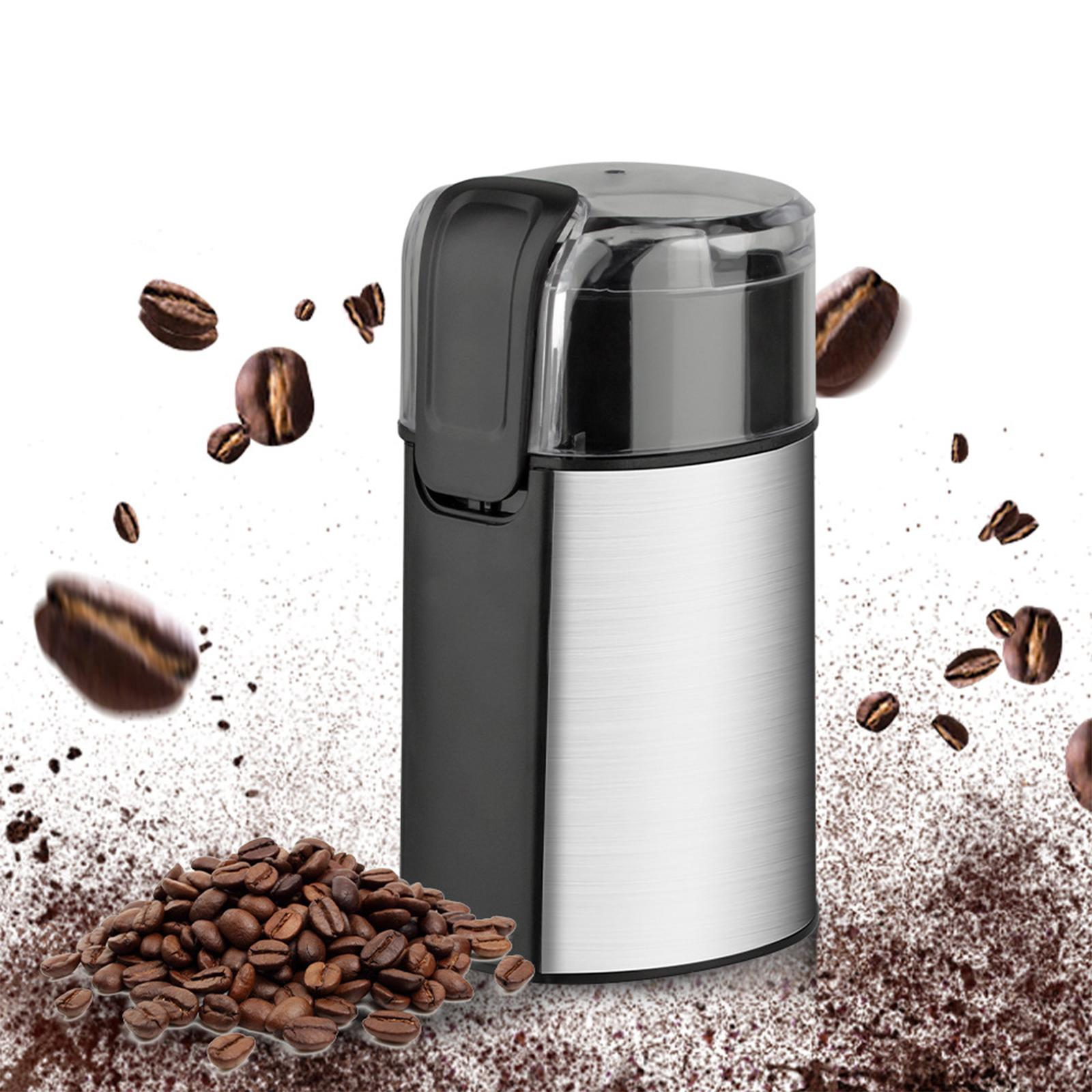 Kaffeemühle mit Kaffeebohnen und gemahlenem Kaffee darum. Bohnen fallen in der Luft.