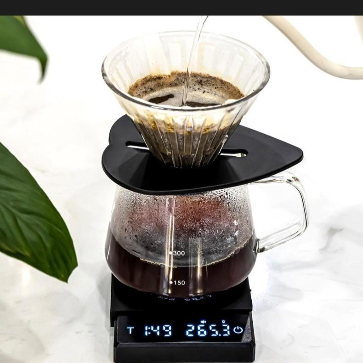 Kaffee wird gebrüht. Eine Glaskaraffe auf einer Waage. Wasser gießt in einen Filter darüber.