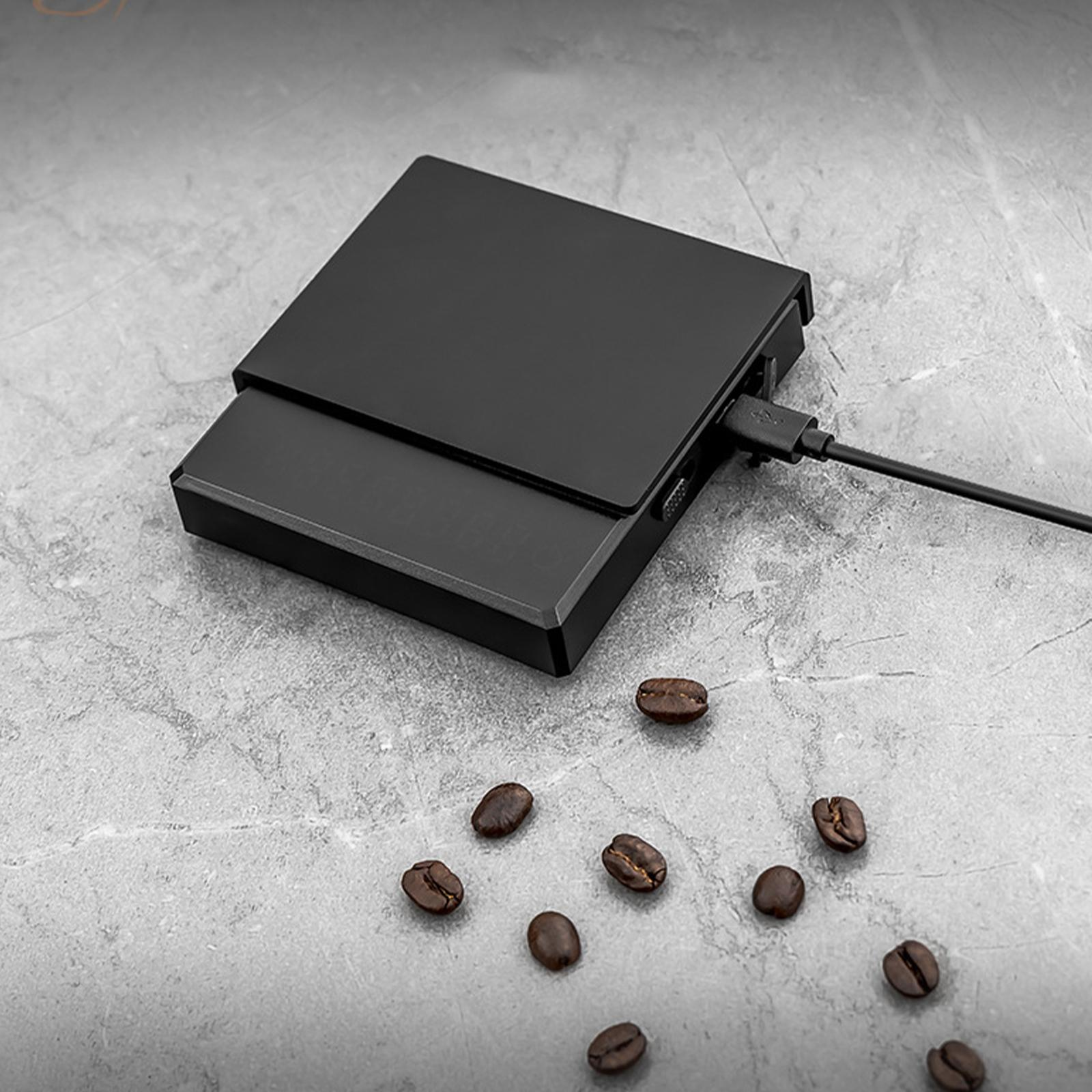 Schwarze Waage mit angeschlossenem USB-Kabel. Kaffeebohnen sind auf der Oberfläche verstreut.