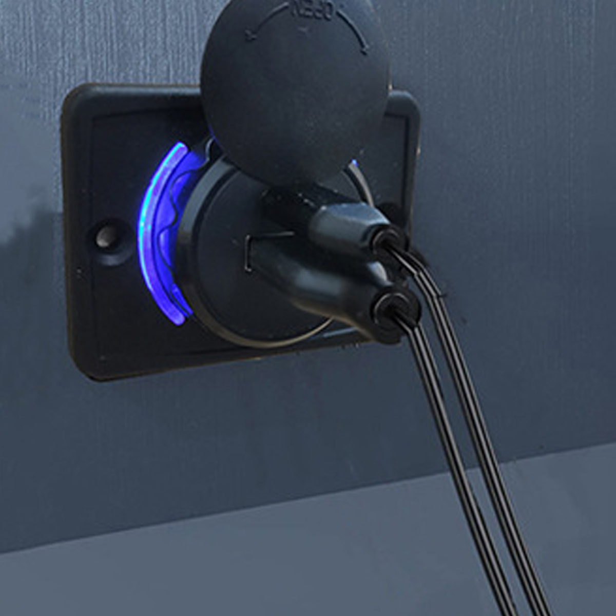 Nahaufnahme eines schwarzen USB-Ladegeräts mit blauem Licht, Kabeln und einem Deckel. Auf dunkler grauer Oberfläche montiert.